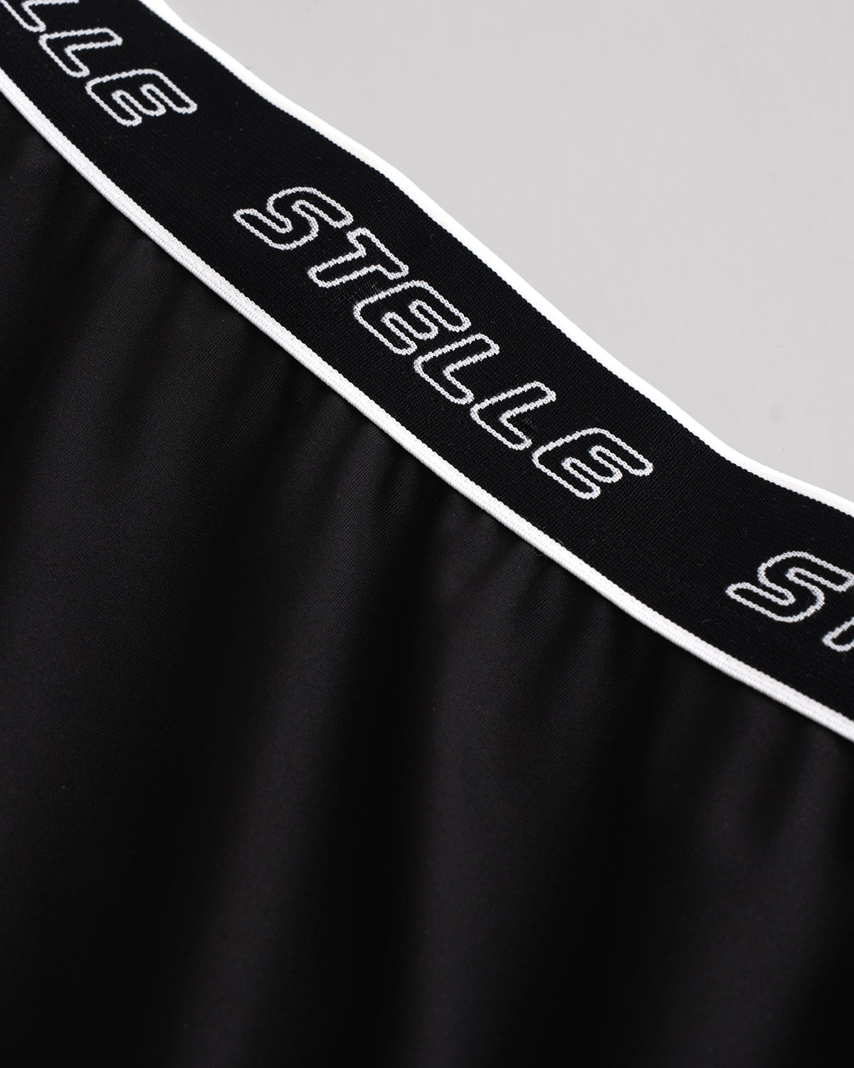 Close-up of the white Stelle logo elastic waistband on the black running shorts.