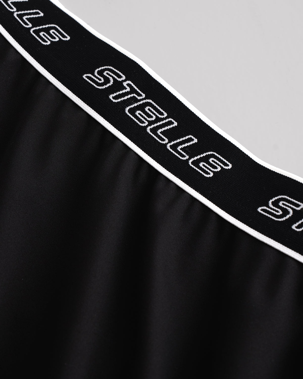 Close-up of the white Stelle logo elastic waistband on the black running shorts.
