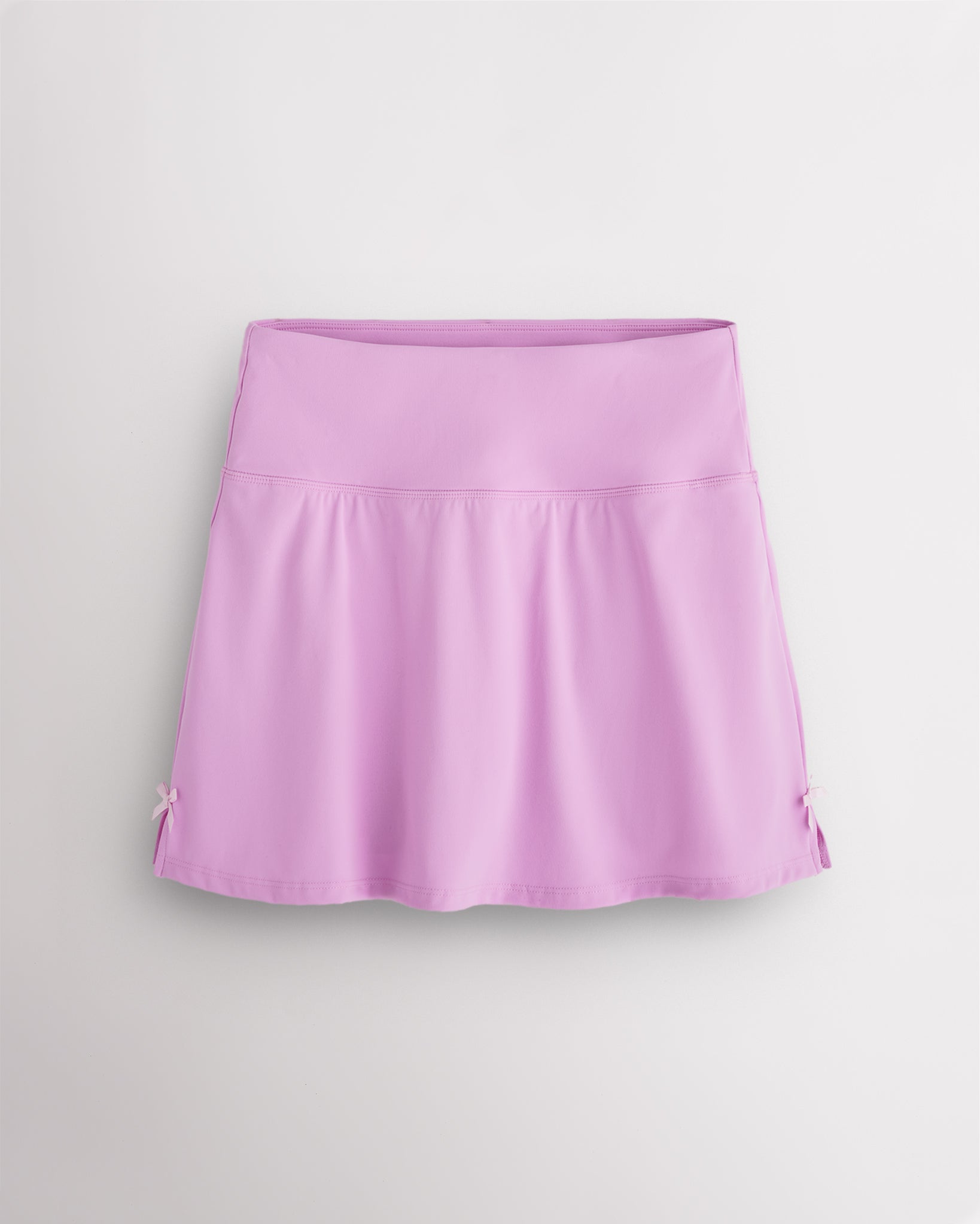 Lilac Stelle classic tennis skirt with a high-waisted fit, slightly flared silhouette, side slits, and bow ribbon details.