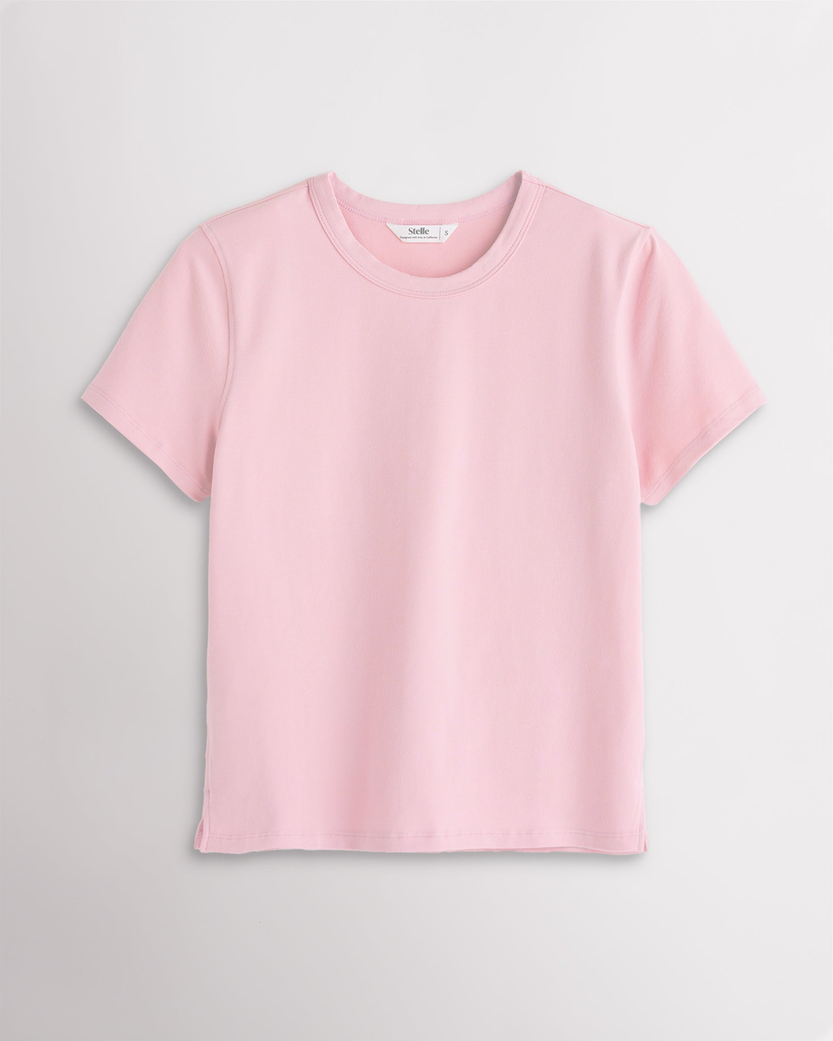 Light Pink Stelle womens short sleeve basic t shirt with crewneck, relaxed boxy fit, and side slits on white background