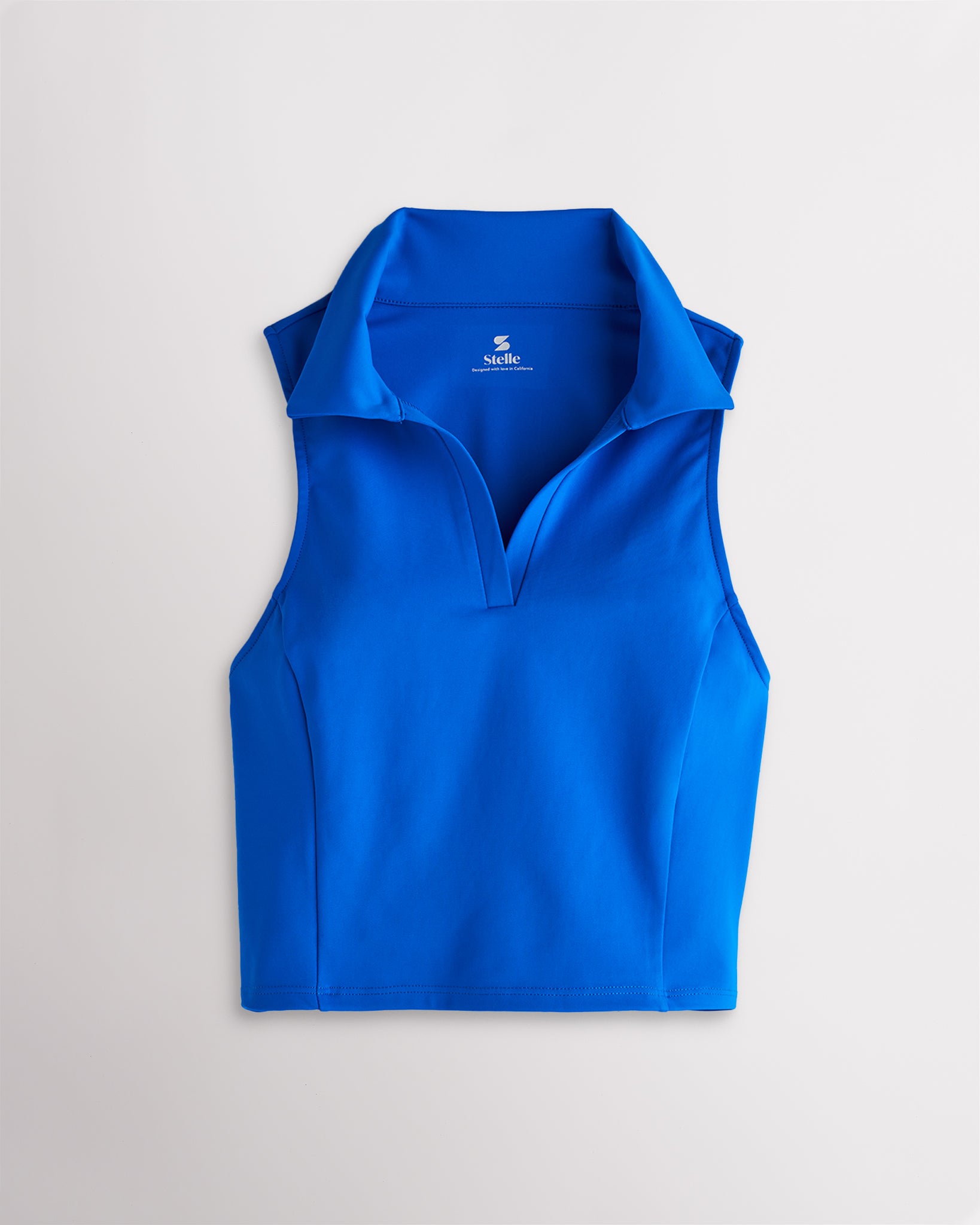 Women’s sapphire fitted cropped polo tank top with a V-neckline, classic collar, sleeveless cut, and contoured seam detailing.