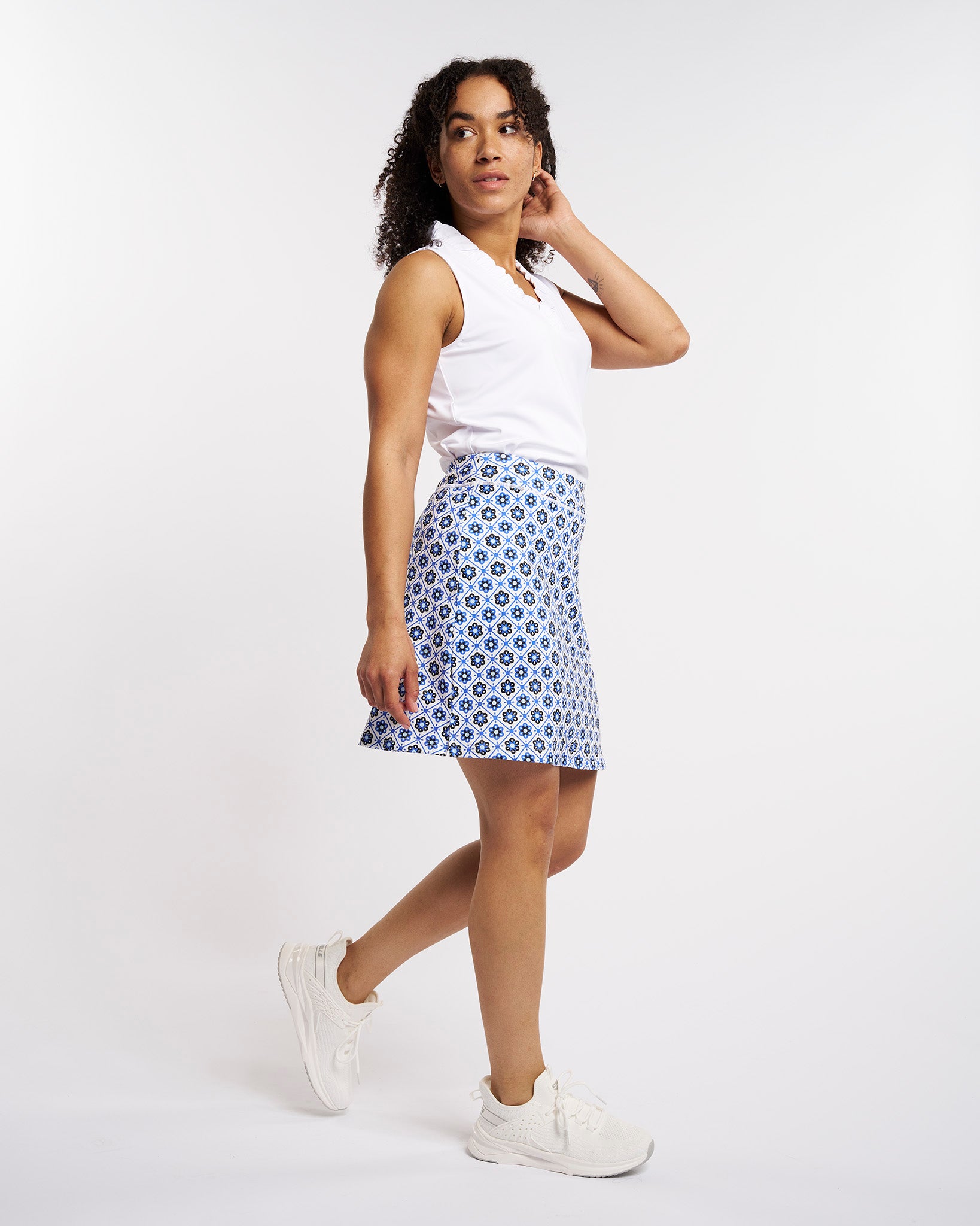 White ruffle V-neck sleeveless polo shirt worn by a woman.
