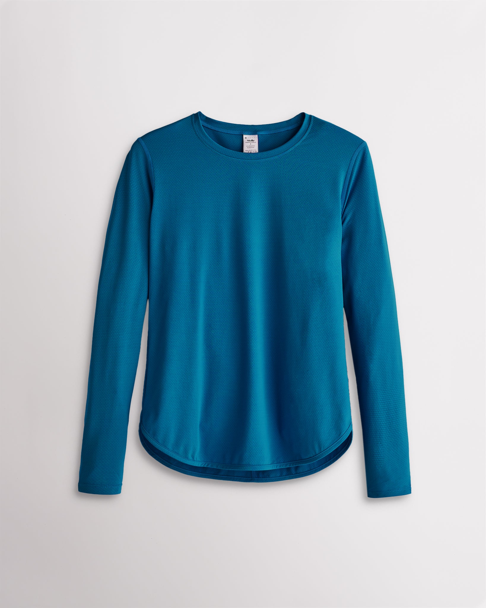 Women’s peacock blue UPF 50+ long sleeve sun protection shirt with curved hem and lightweight breathable fabric.