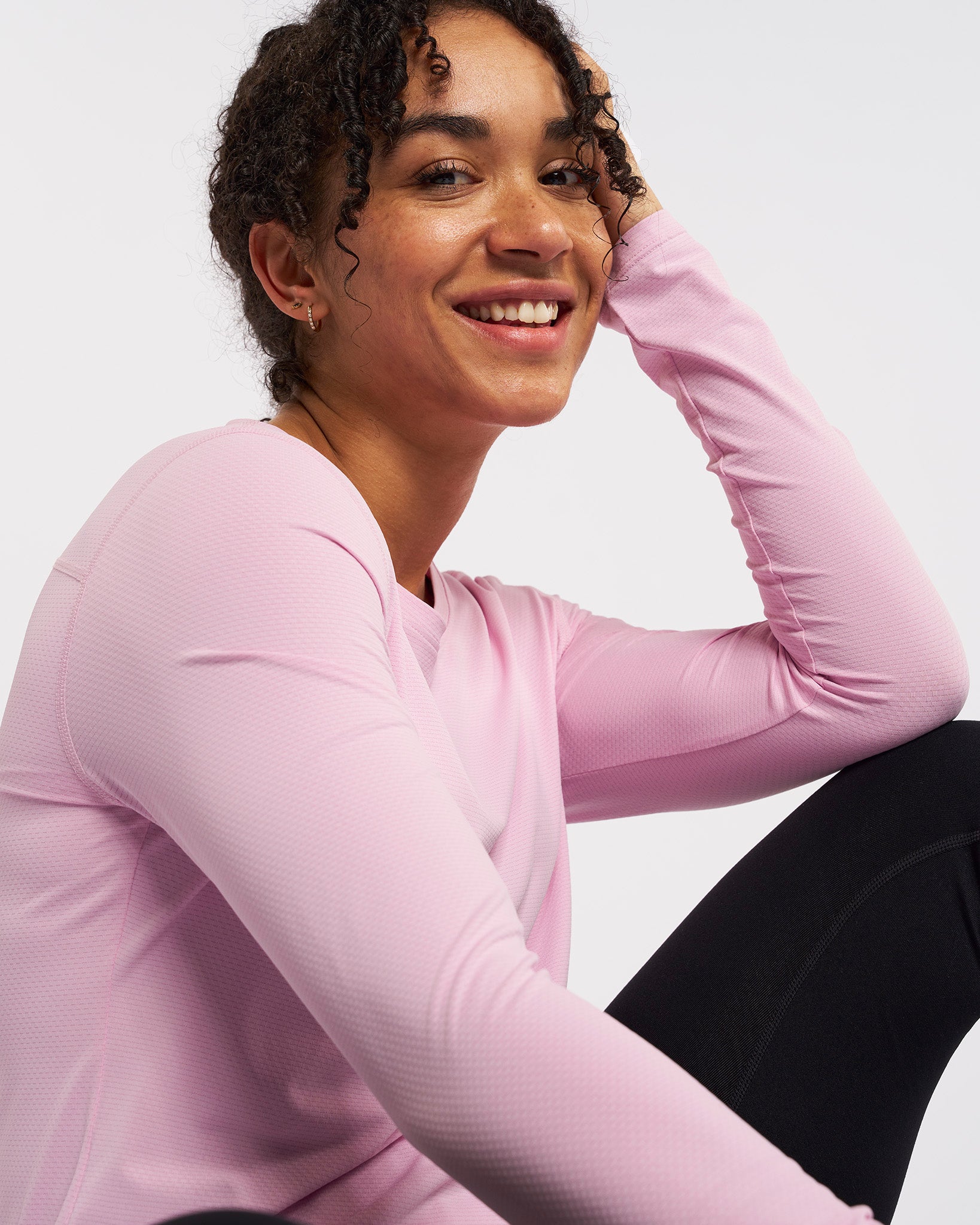 Close-up of woman in petal pink UPF 50+ long sleeve sun protective shirt, soft breathable fabric, comfortable fit for outdoor activities.