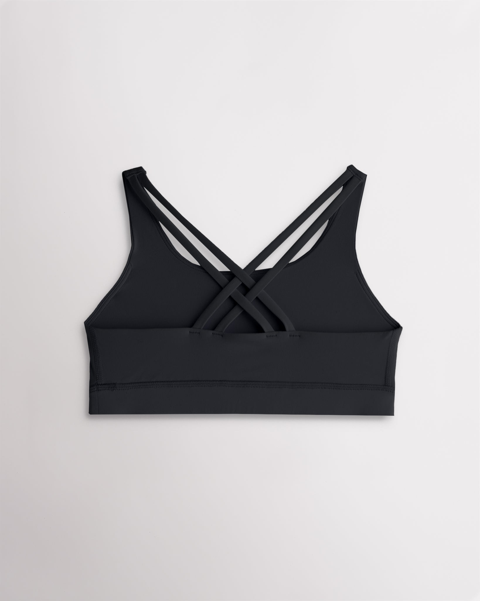 Back view of a girls black sports bra featuring multiple criss-cross straps and a wide supportive band.