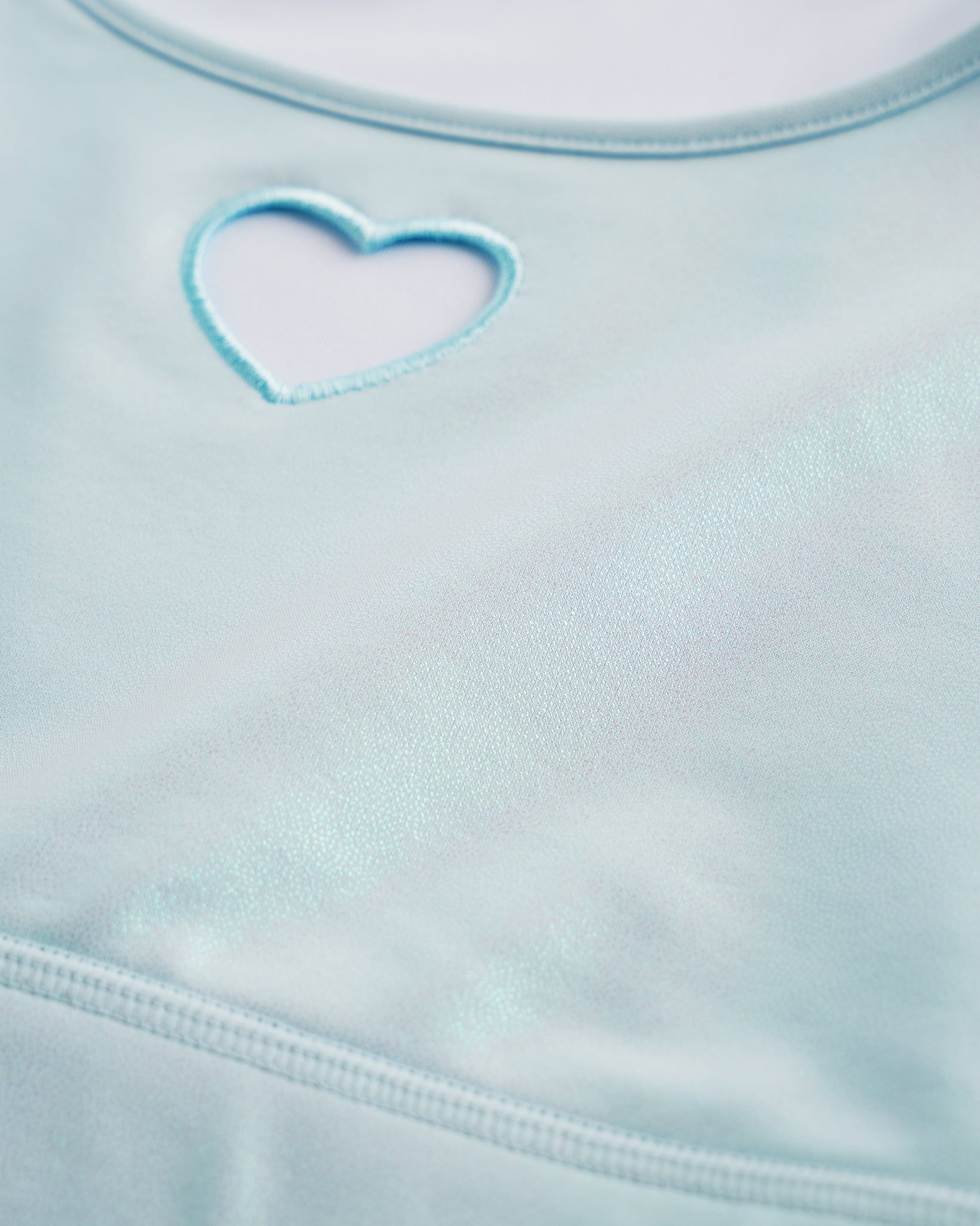 Close-up of Light Blue shimmer crop top showing heart cutout detail, smooth stitching, and iridescent fabric.