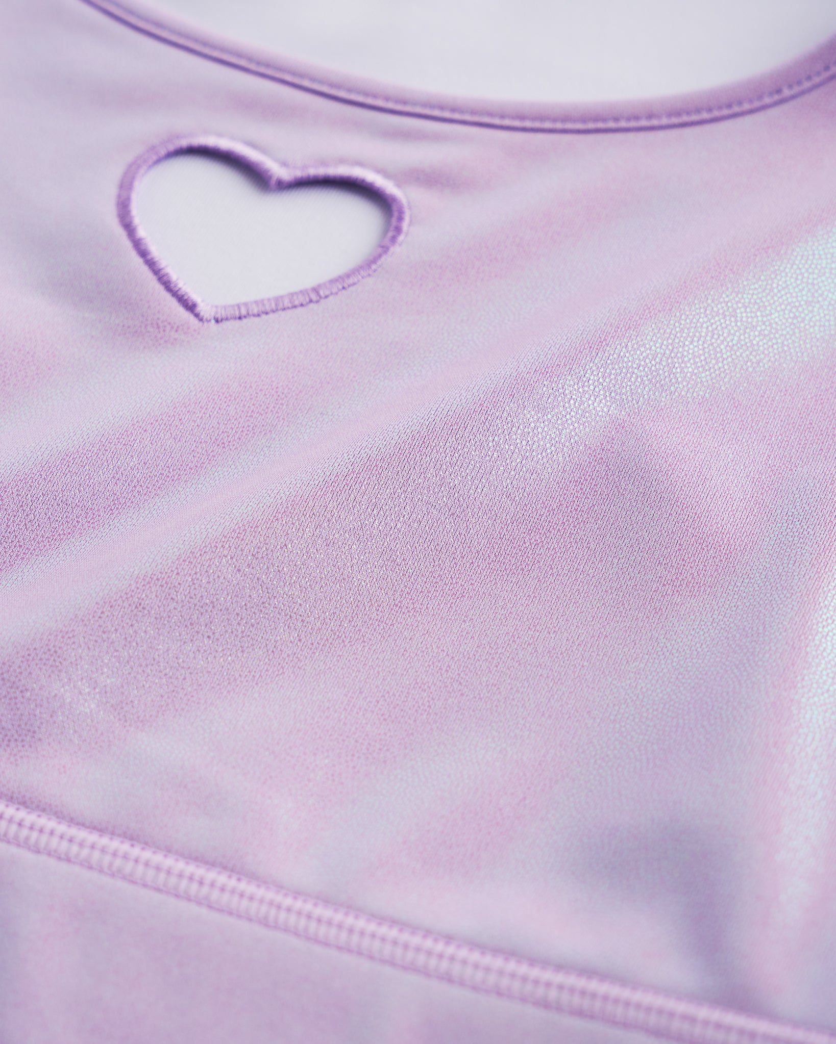 Close-up of lavender shimmer crop top showing heart cutout detail, smooth stitching, and iridescent fabric.