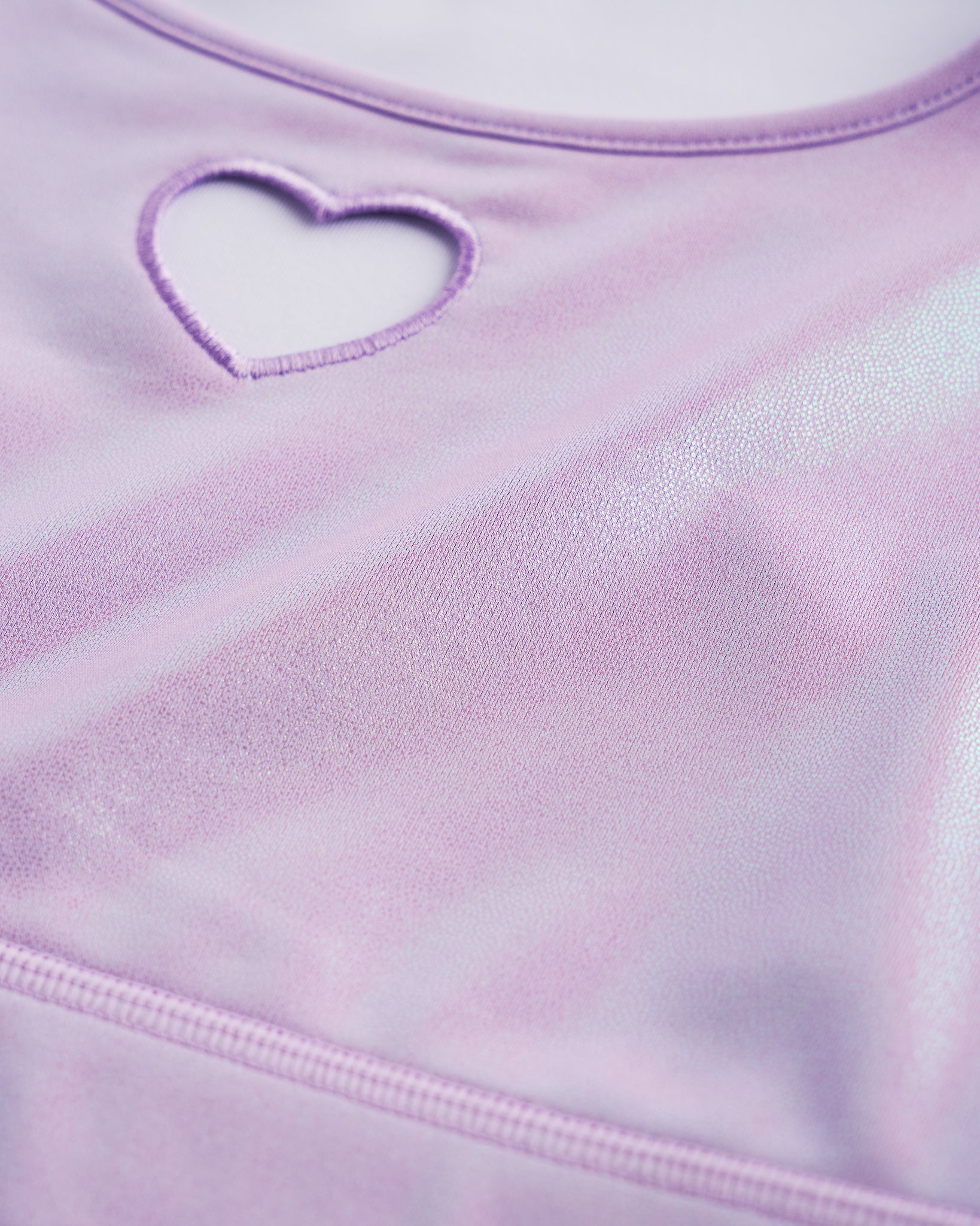Close-up of lavender shimmer crop top showing heart cutout detail, smooth stitching, and iridescent fabric.