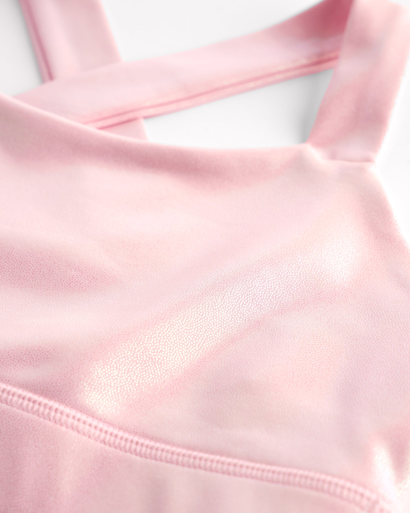 Close-up of pink metallic girls tank top showing iridescent shimmer fabric and smooth seam detail.