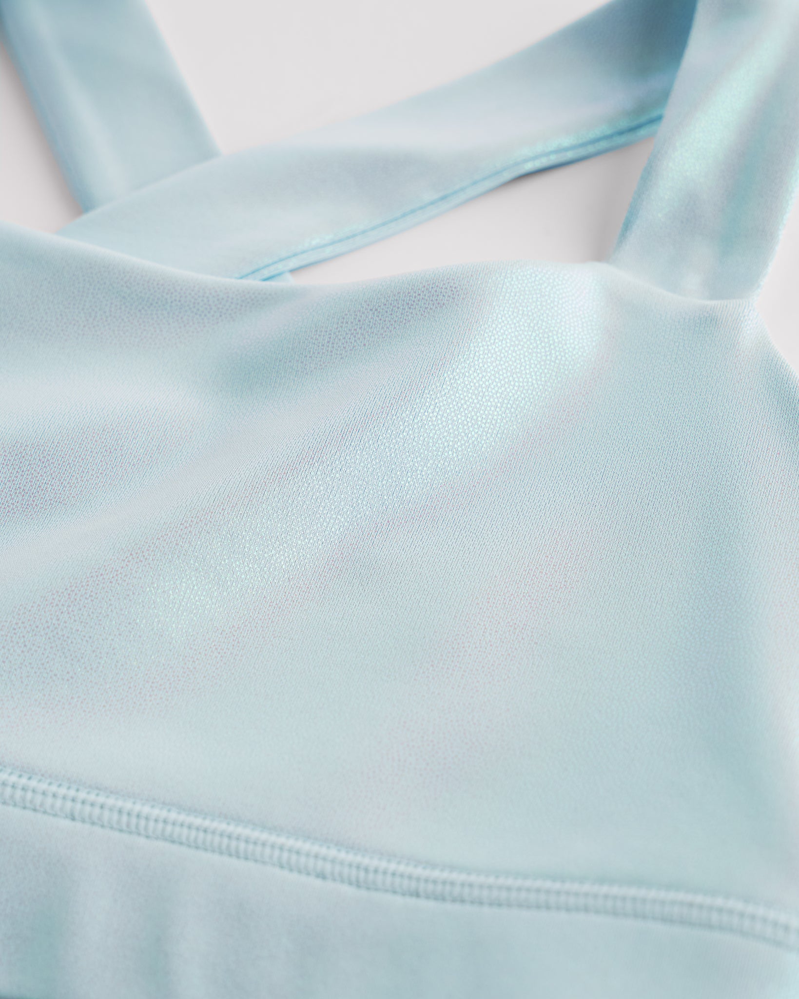 Close-up of light blue metallic girls tank top showing iridescent shimmer fabric and smooth seam detail.