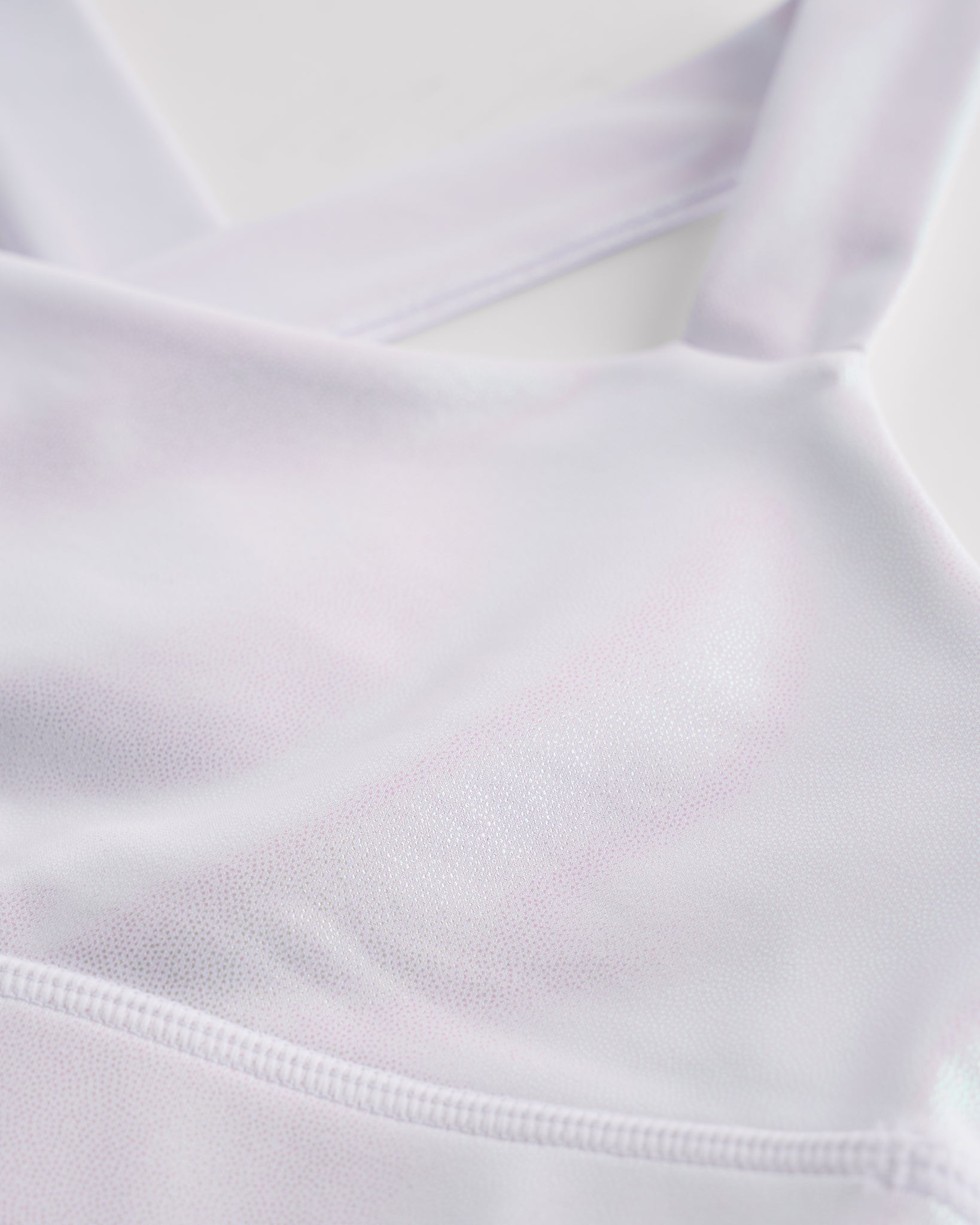 Close-up of white metallic girls tank top showing iridescent shimmer fabric and smooth seam detail.