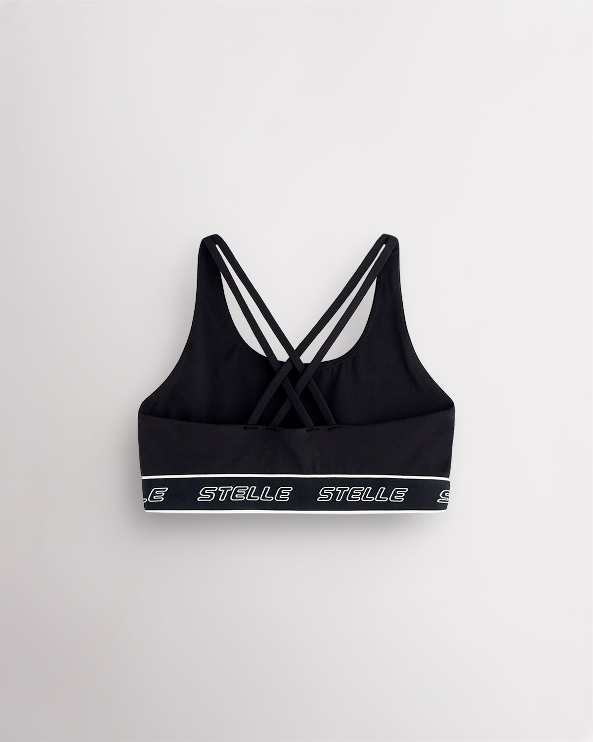 Back of the black Stelle girls sports bra laid flat, showing the criss-cross straps.
