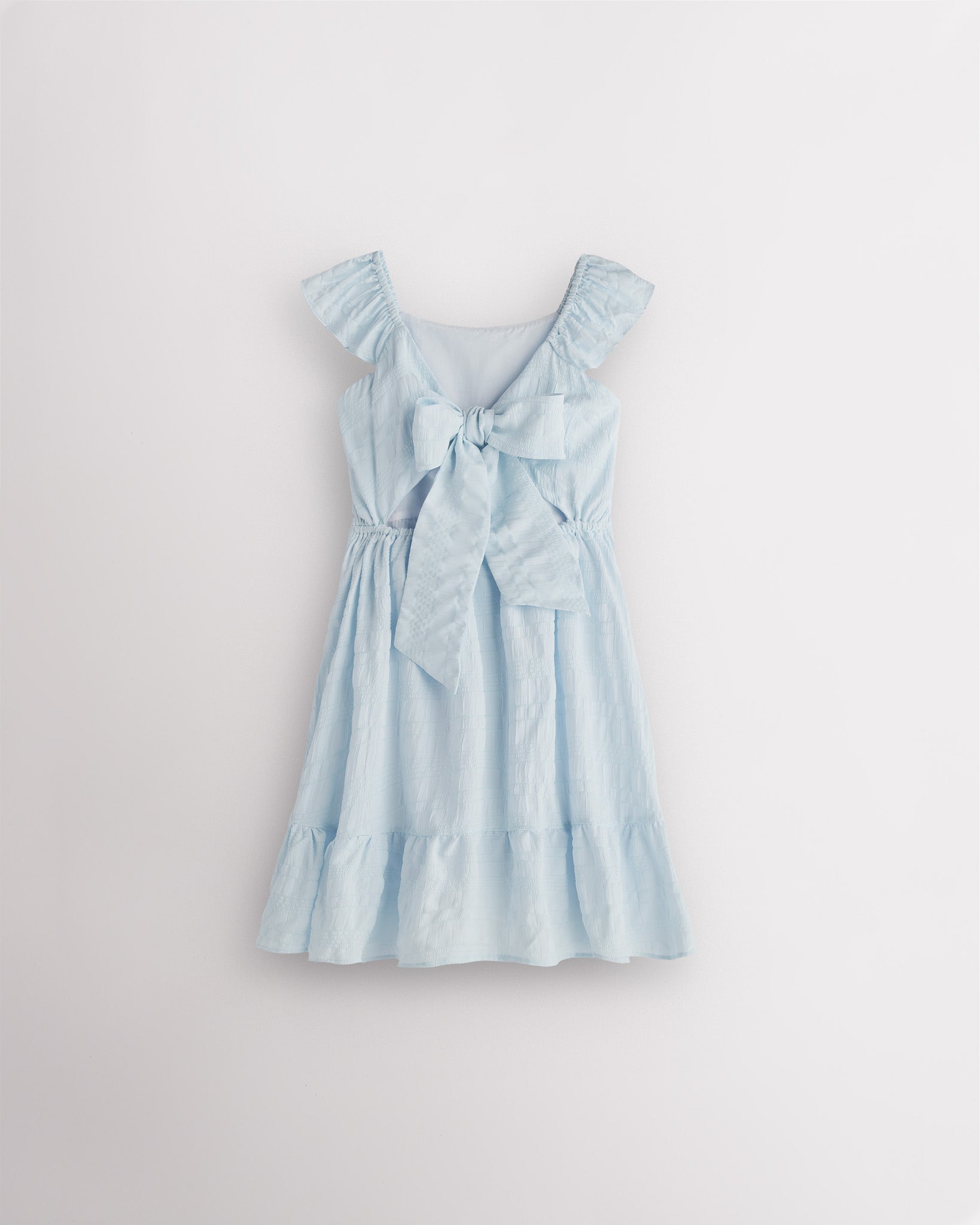 Girls light blue flutter sleeve sundress with adjustable bow back, smocked waist, and tiered skirt, back view showing bow detail
