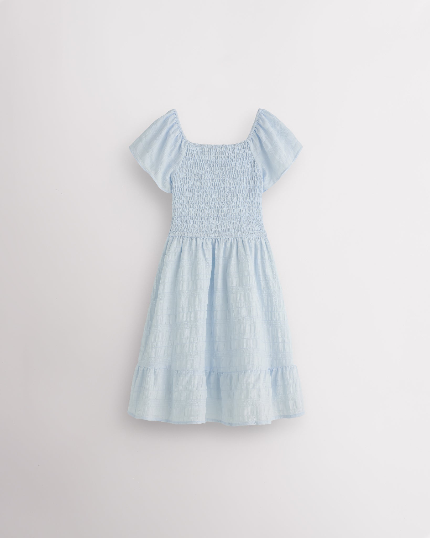 Back view of light blue girls summer dress showing smocked back, short sleeves, and soft gathered skirt.