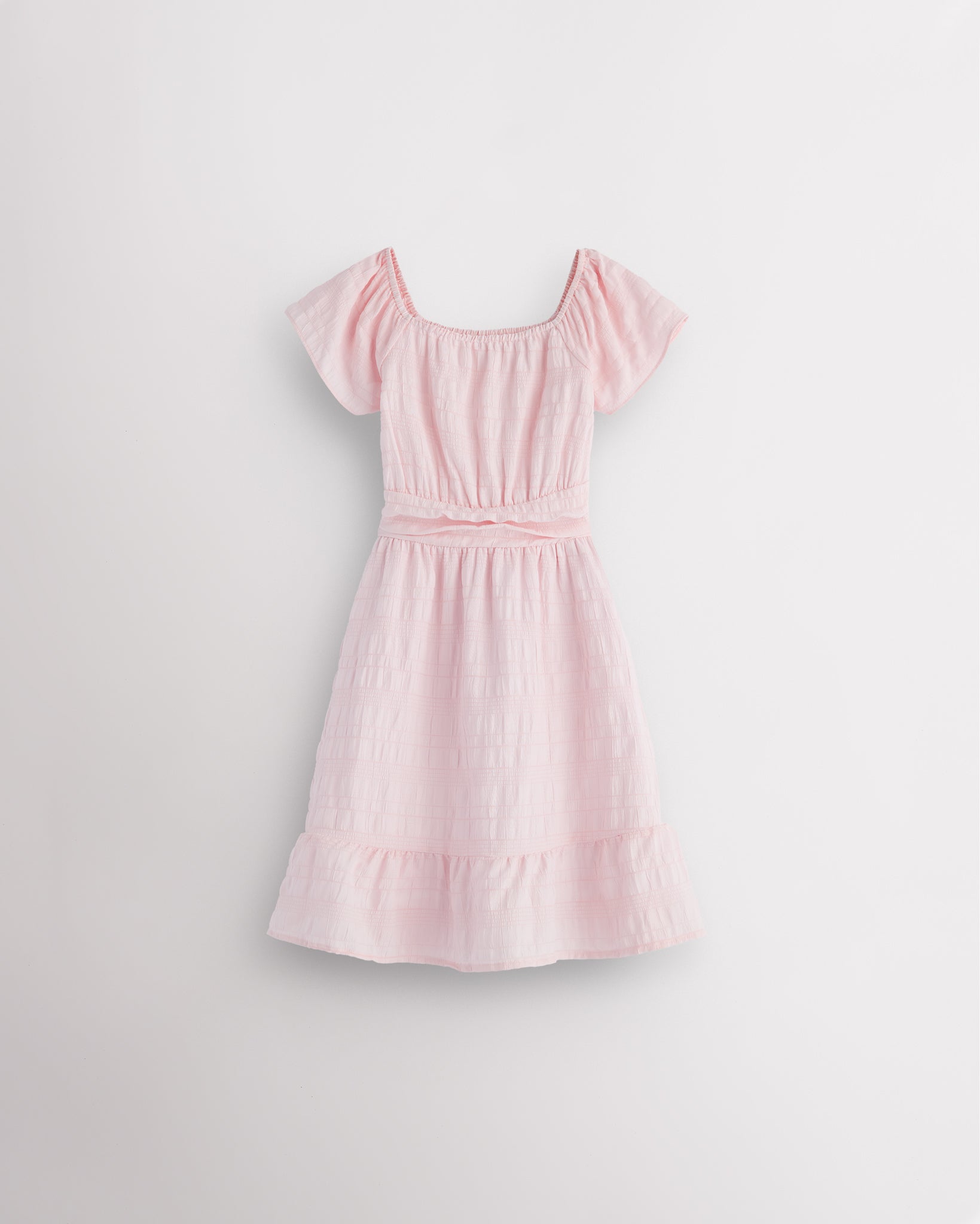 Light pink girls smocked summer dress with short sleeves, square neck, fit-and-flare shape, and ruffle hem.