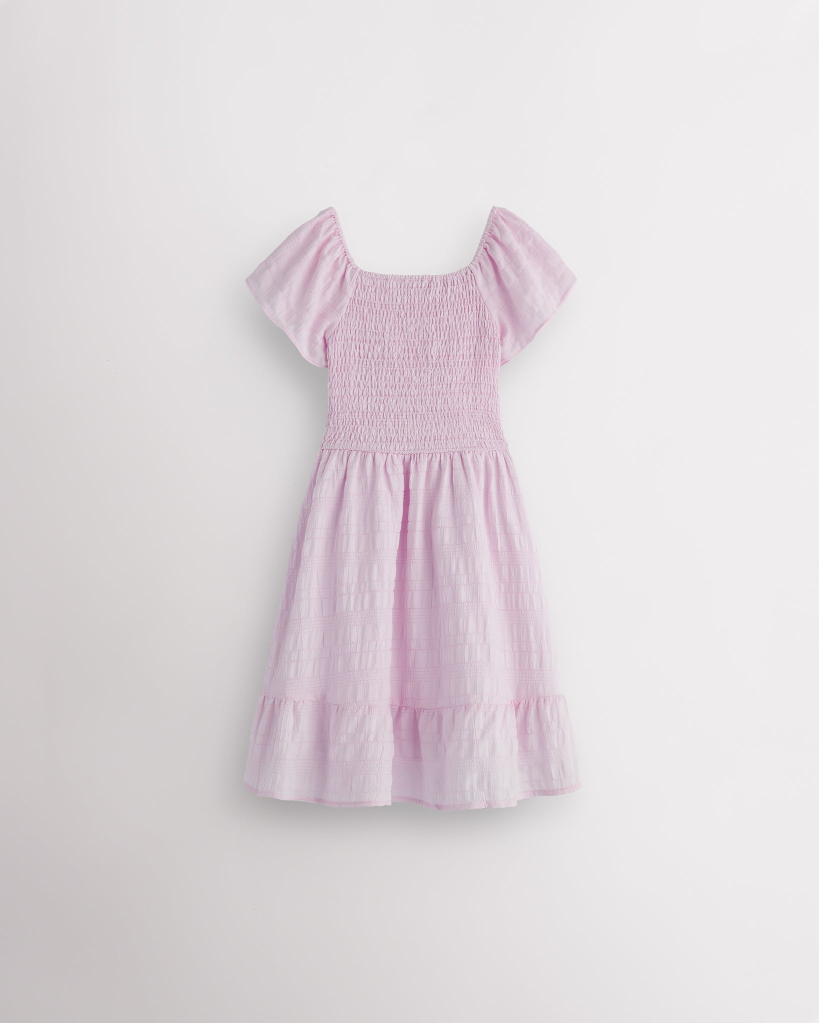 Back view of lilac girls summer dress showing smocked back, short sleeves, and soft gathered skirt.