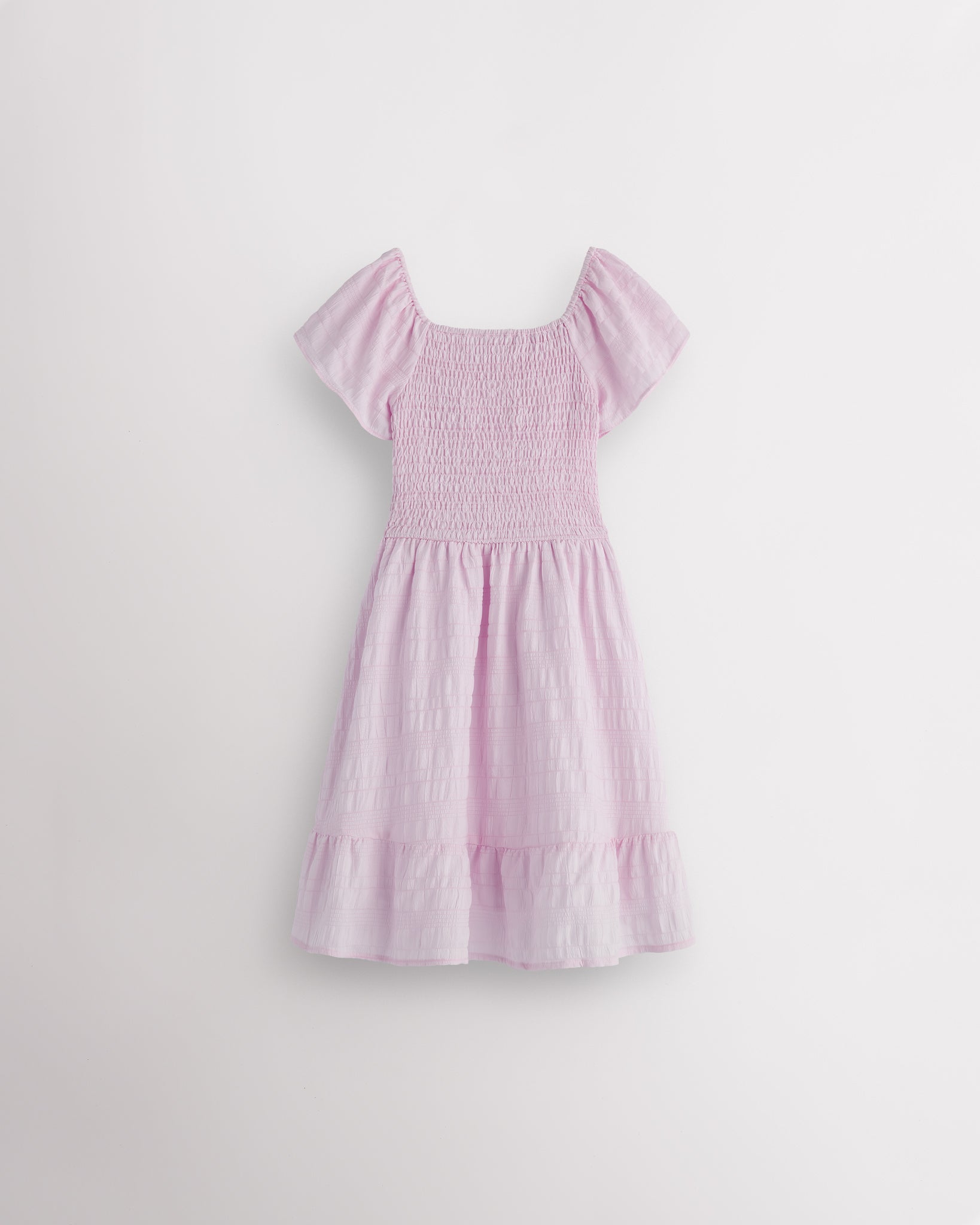 Back view of lilac girls summer dress showing smocked back, short sleeves, and soft gathered skirt.