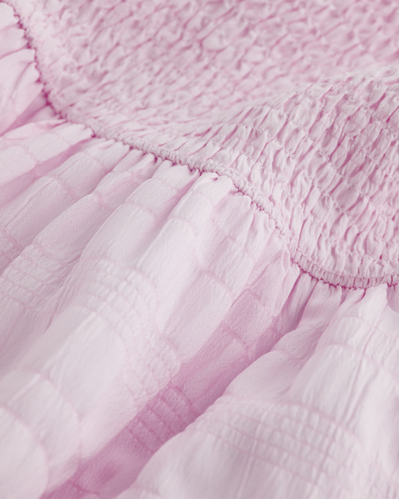 Close-up of lilac smocked fabric and gathered waist detail on Stelle girls dress.