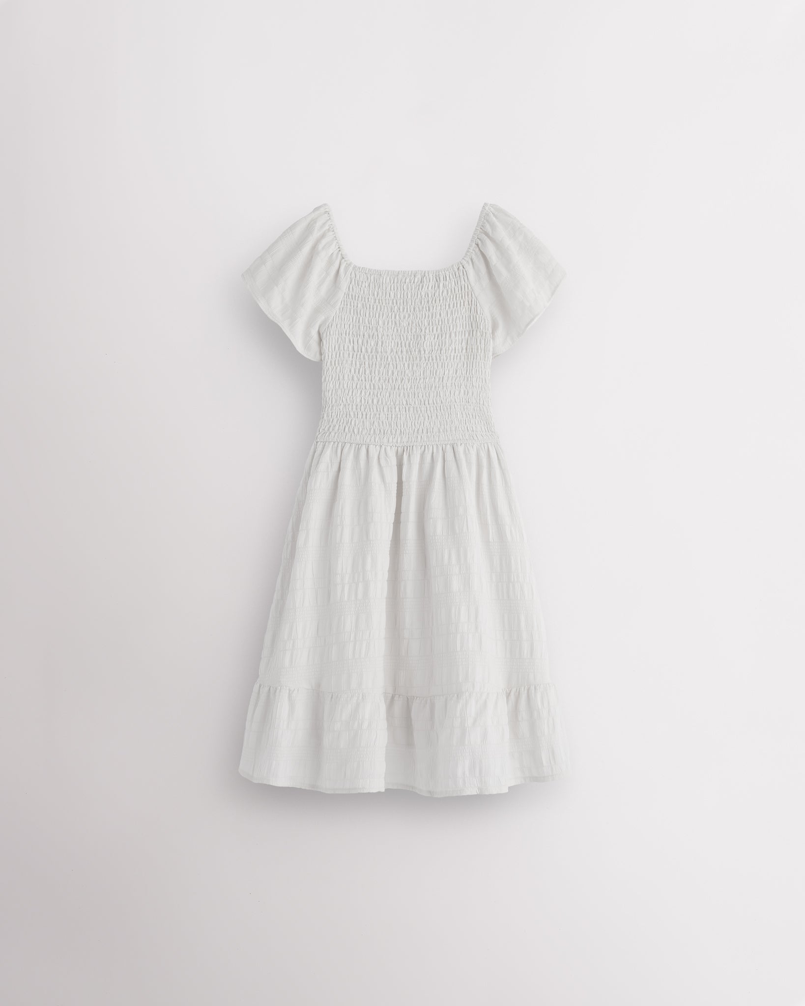 Back view of white girls summer dress showing smocked back, short sleeves, and soft gathered skirt.