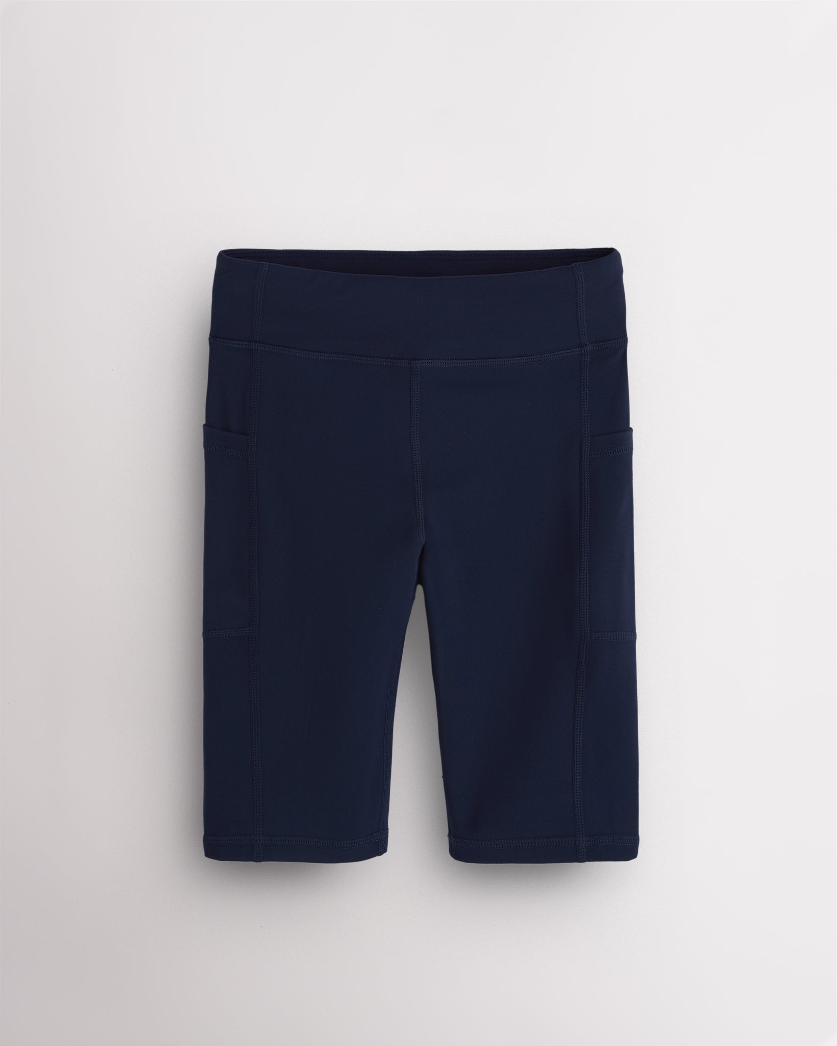 Navy girls 8-inch volleyball shorts with side pockets, wide waistband, seamless front, and stretch-knit fabric for court and active wear.