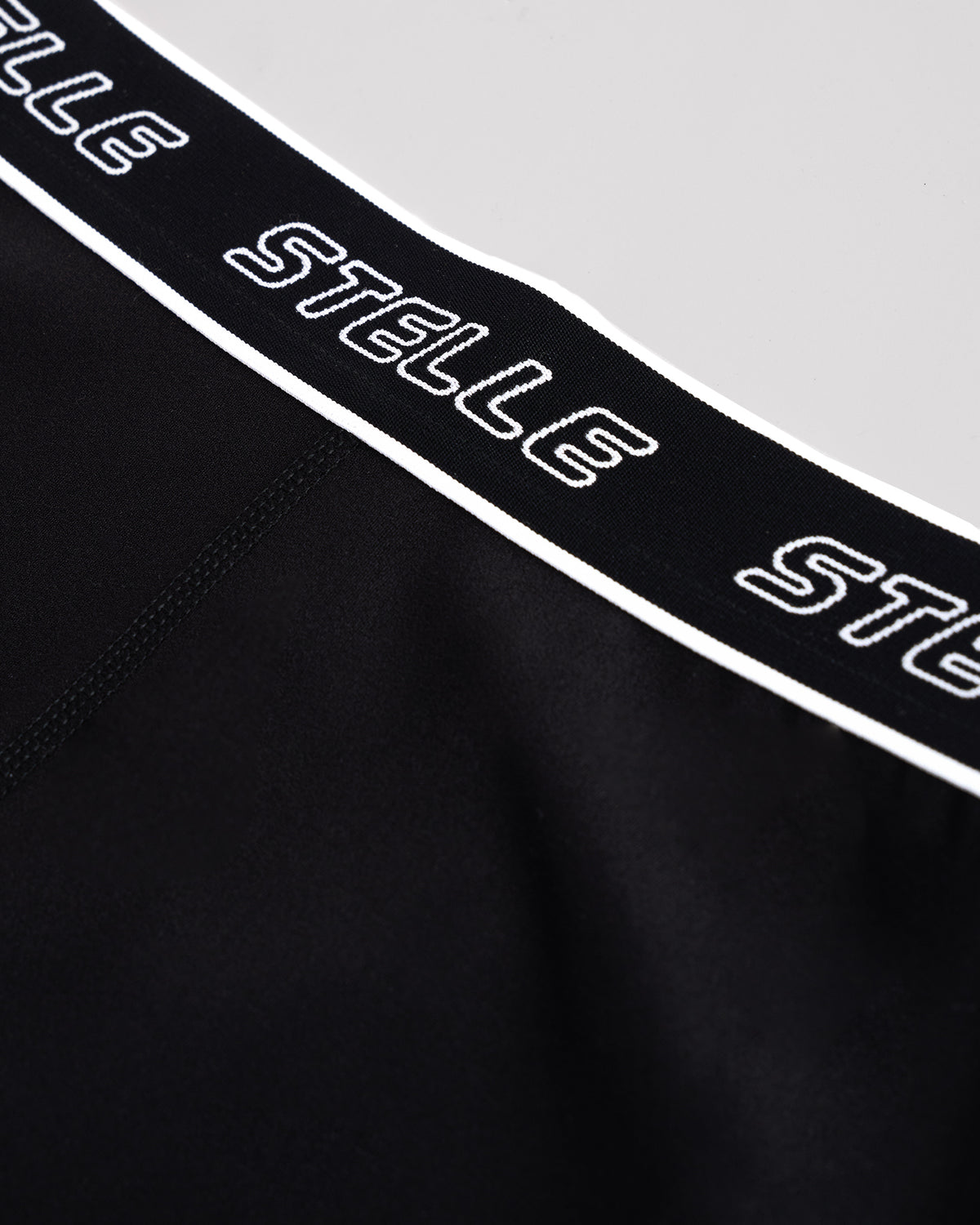 Detail of the repeating Stelle logo on the elastic waistband of the black girls leggings.