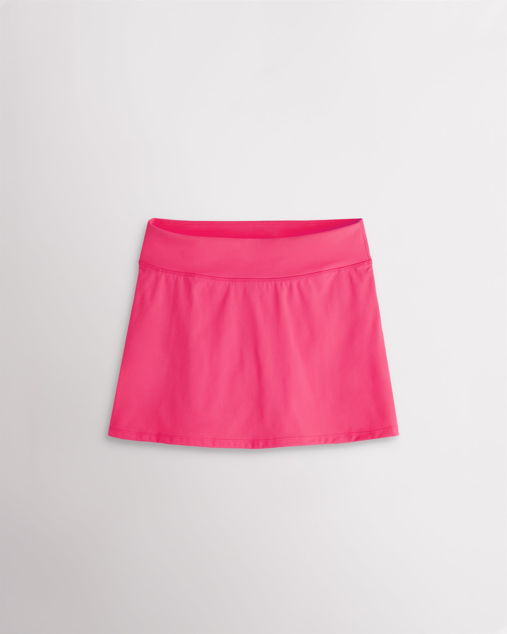 A quick-dry dreamhouse pink tennis skirt with a smooth front, ruffle back hem, and built-in shorts with pockets for comfortable coverage on and off the court.