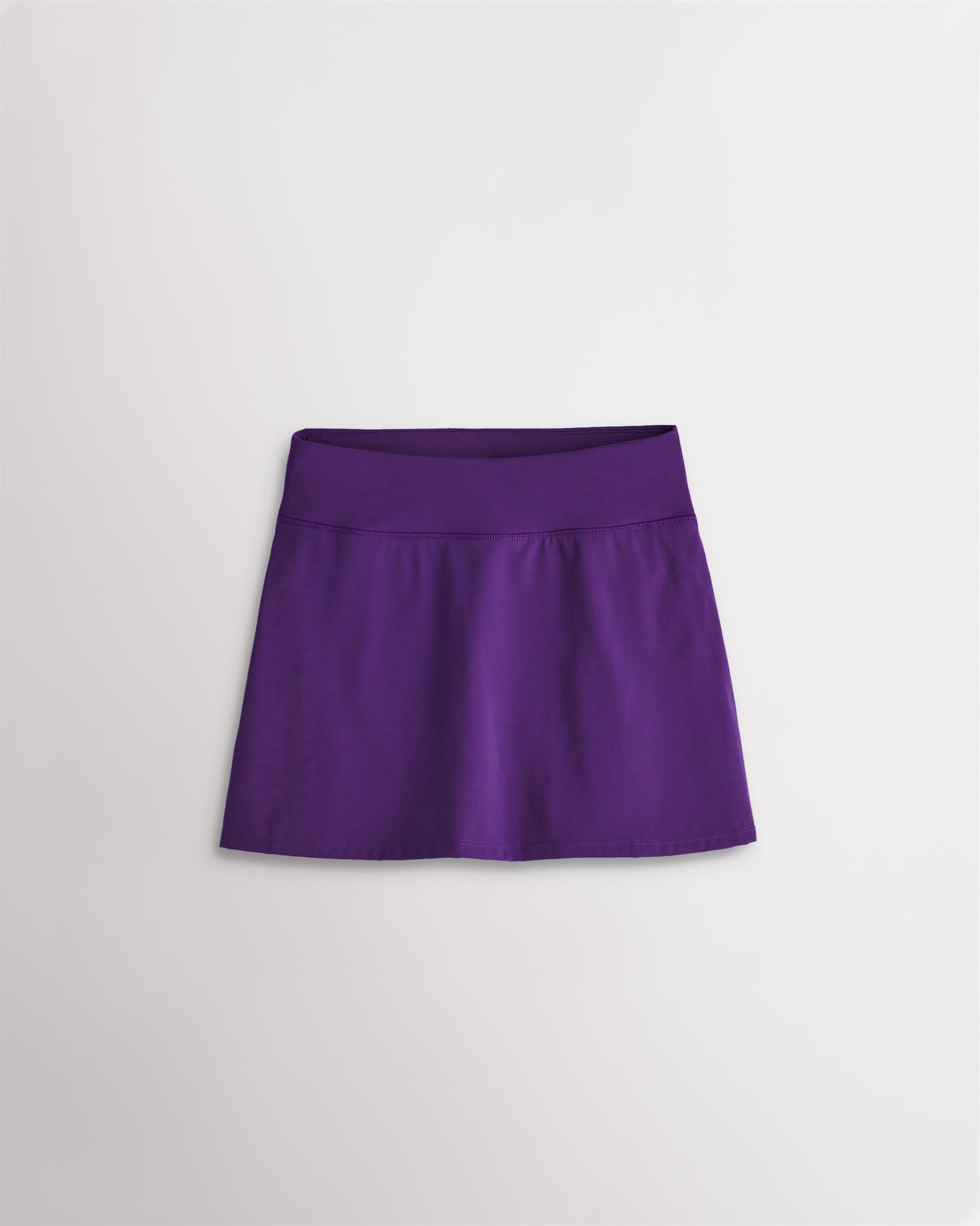 A quick-dry purple tennis skirt with a smooth front, ruffle back hem, and built-in shorts with pockets for comfortable coverage on and off the court.