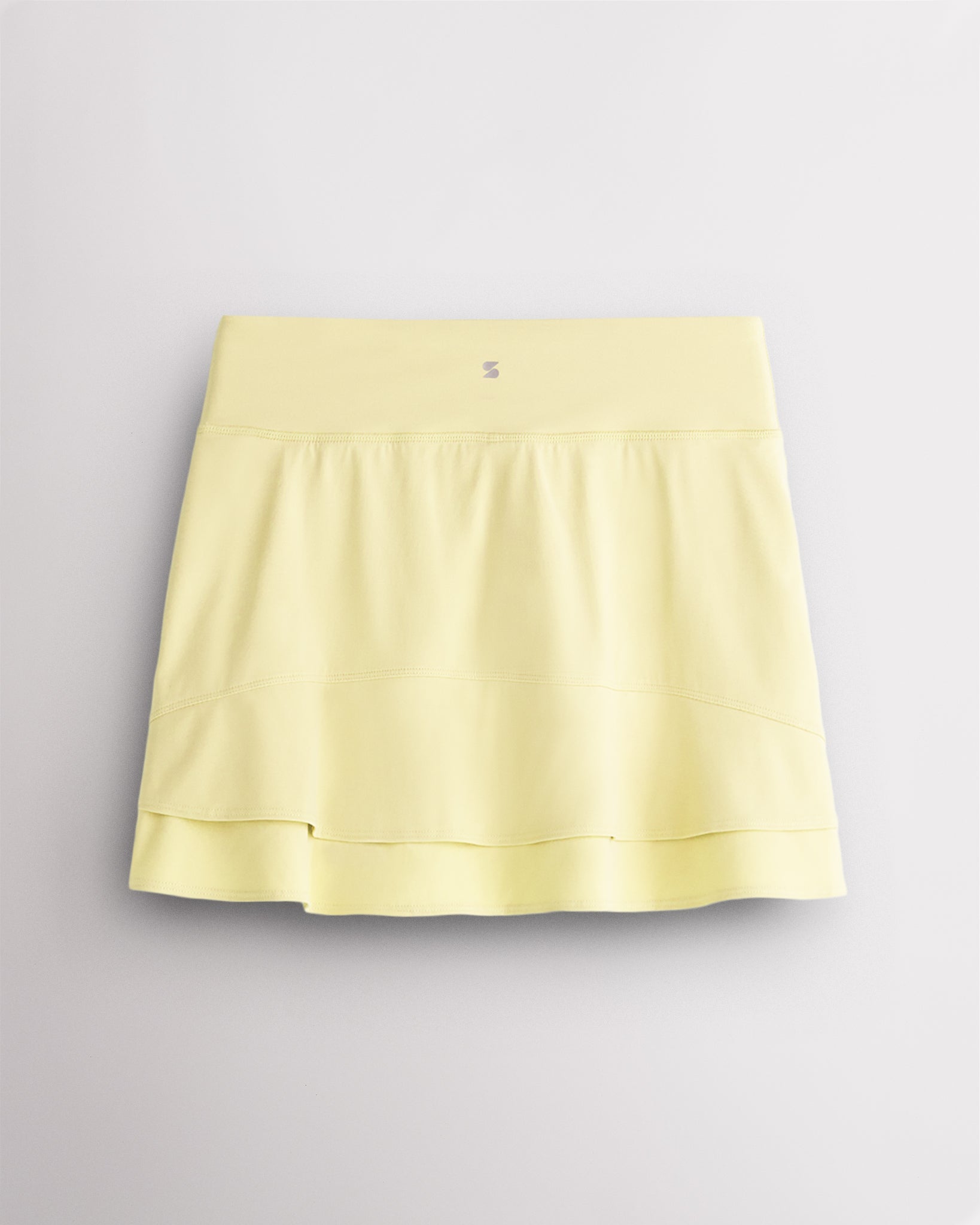 Back view of Lemon Butter Stelle Ruffle Ace tennis skirt showing double-layer ruffle detail, high waistband, and Stelle logo.