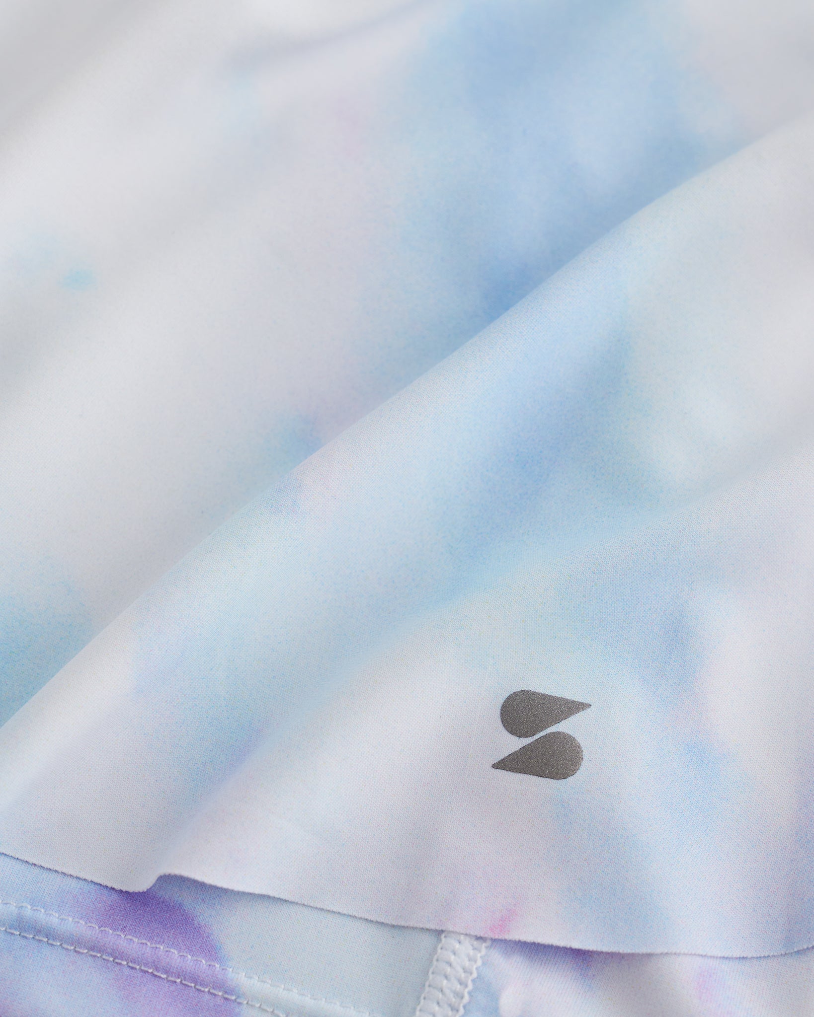 Close-up of Lilac Sky flowy shorts showing soft printed fabric, hem detail, and small Stelle logo.