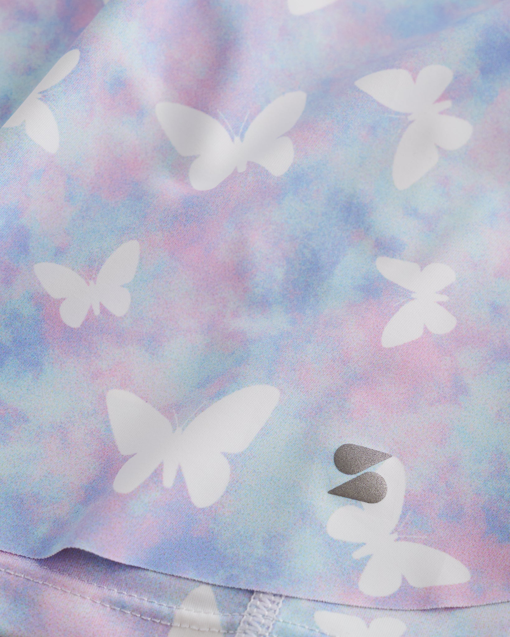Close-up of Magic Flutter flowy shorts showing soft printed fabric, hem detail, and small Stelle logo.