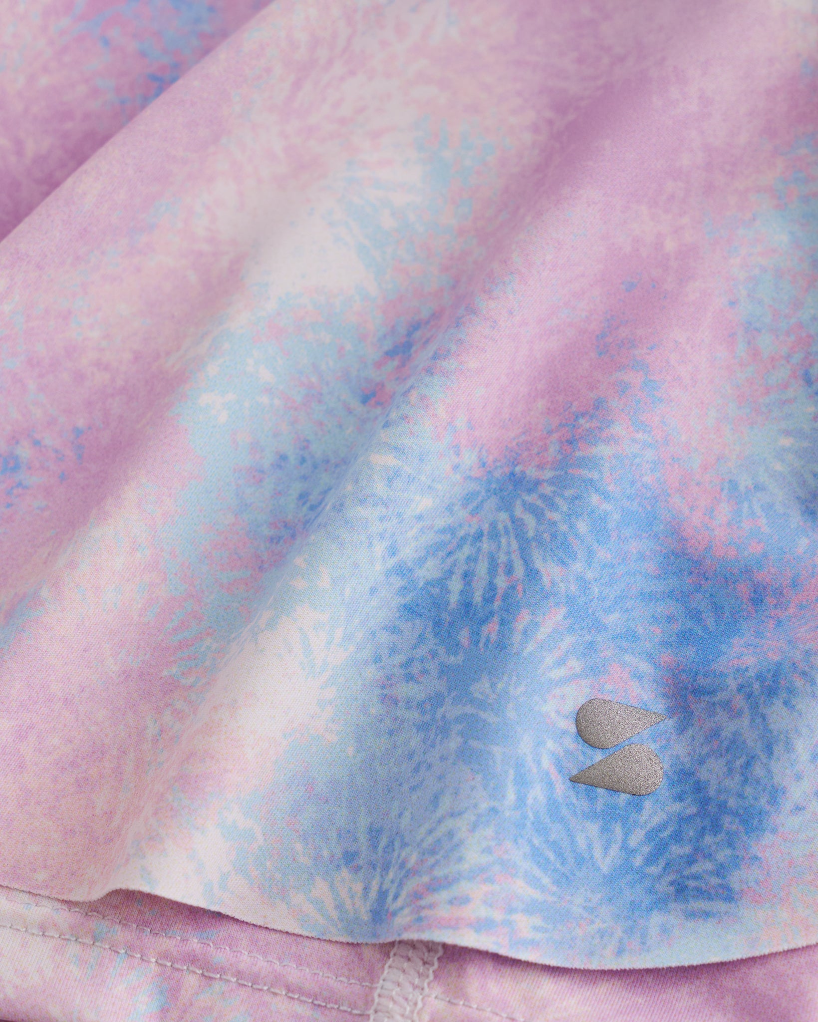 Close-up of Tie Dye Marshmallow flowy shorts showing soft printed fabric, hem detail, and small Stelle logo.