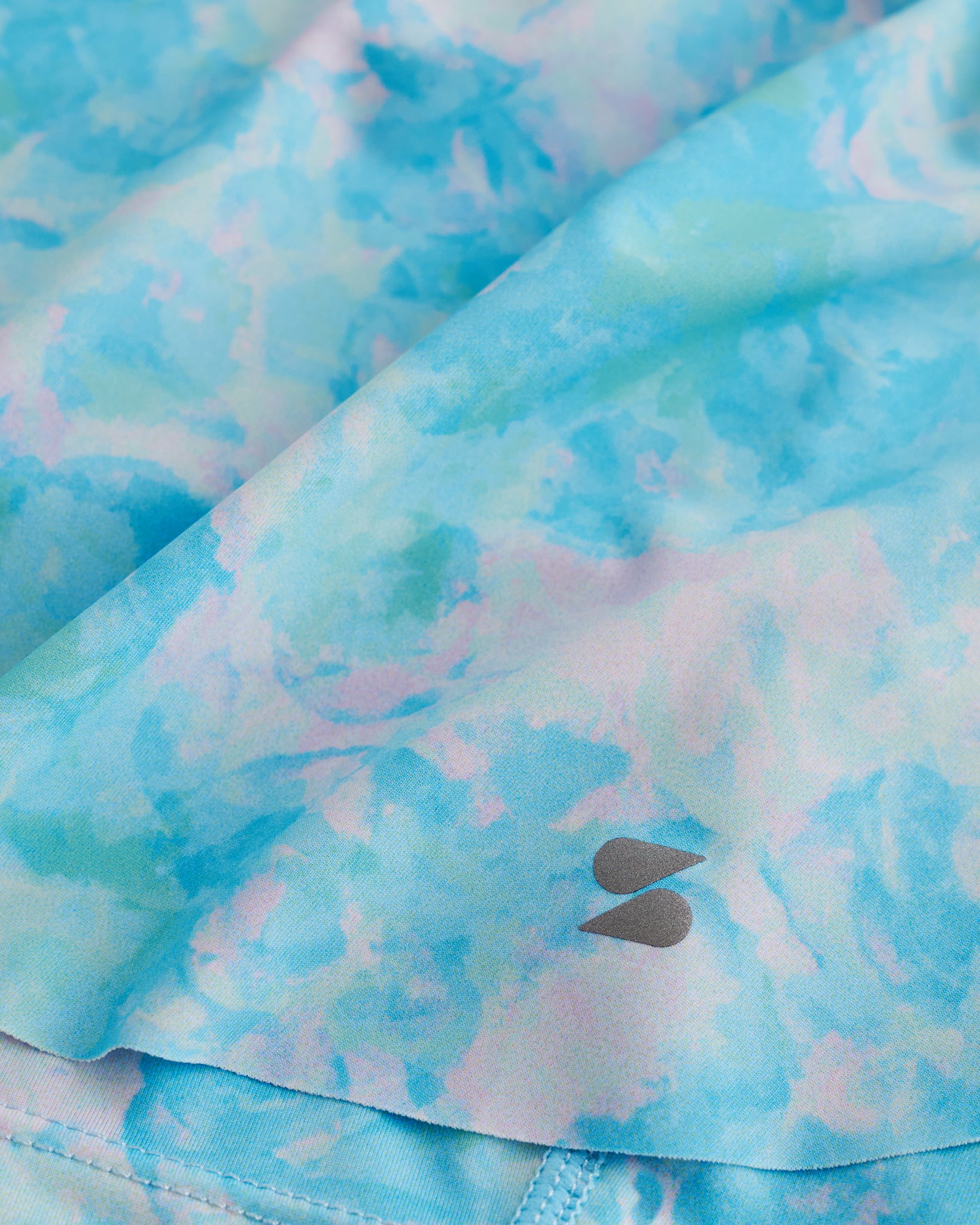 Close-up of Blue Meadow flowy shorts showing soft printed fabric, hem detail, and small Stelle logo.