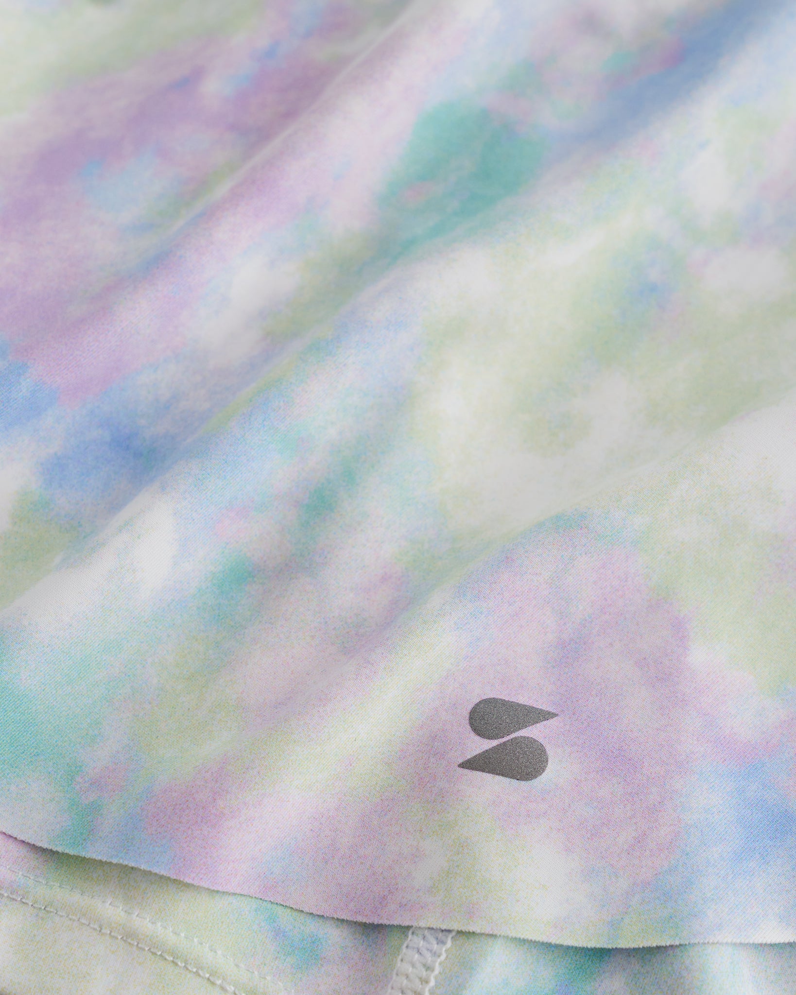 Close-up of Spring Mist flowy shorts showing soft printed fabric, hem detail, and small Stelle logo.