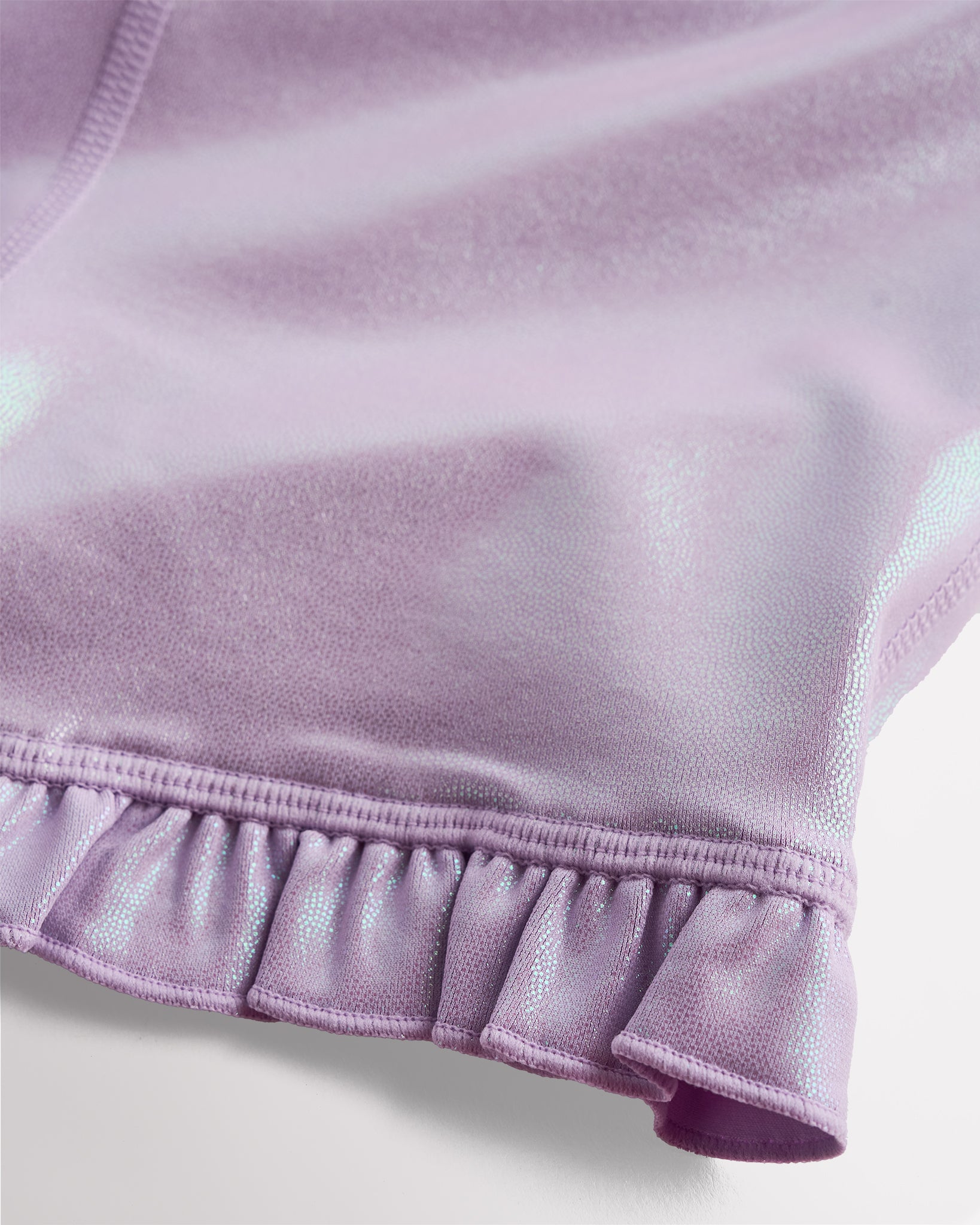 Close-up of lavender shimmer active shorts showing iridescent fabric and ruffle hem detail