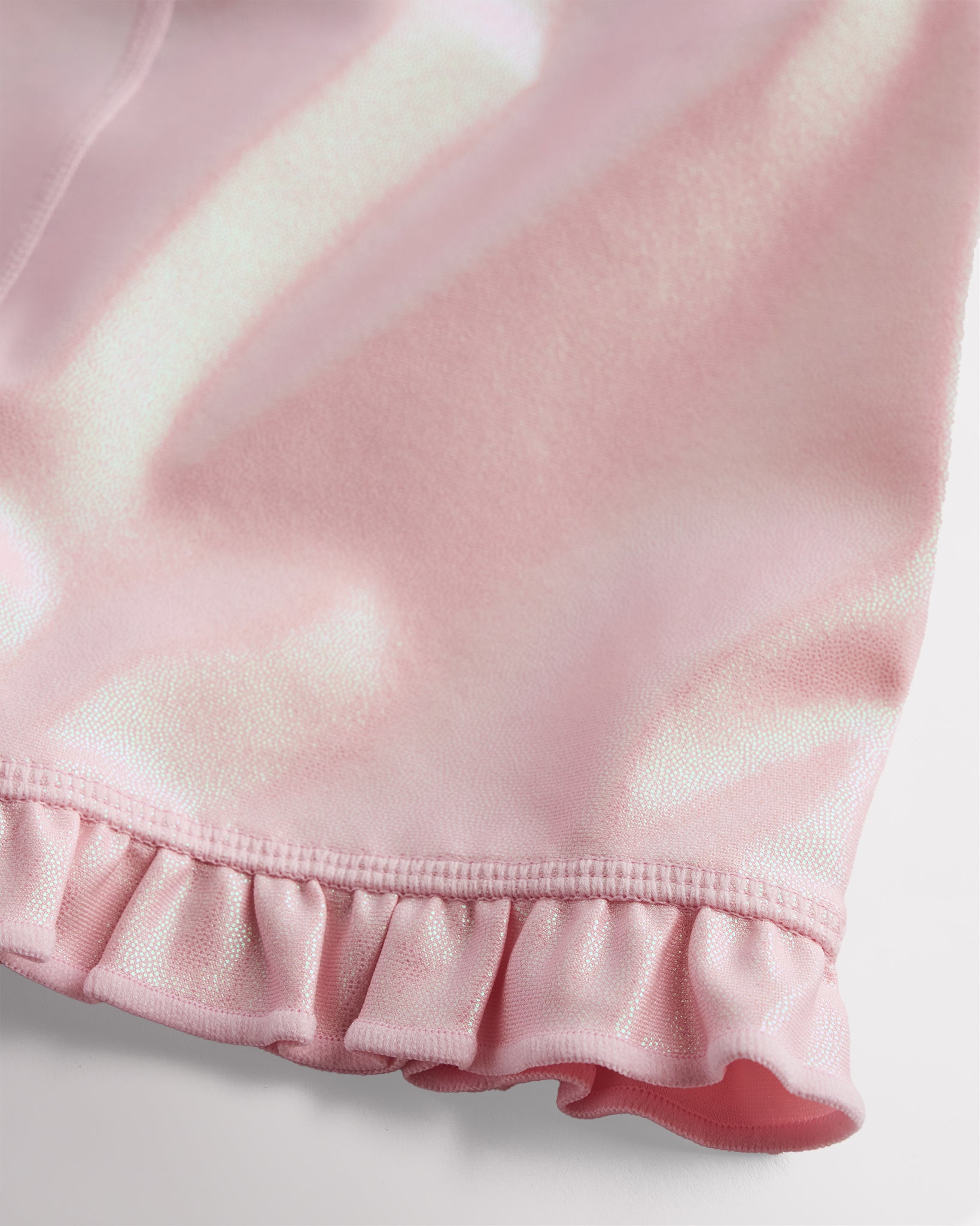 Close-up of pink shimmer active shorts showing iridescent fabric and ruffle hem detail
