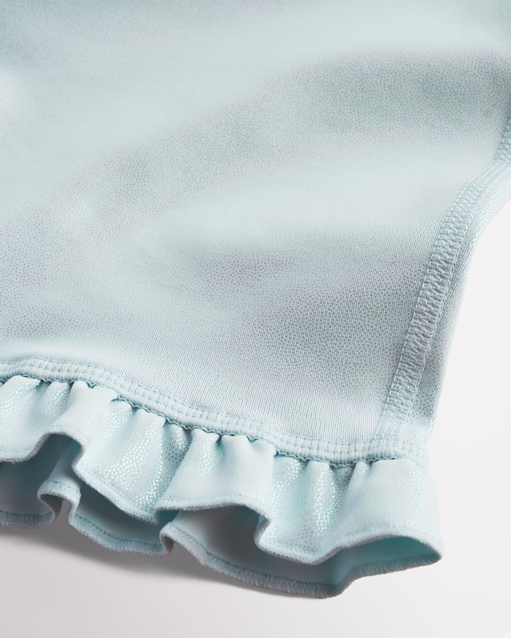 Close-up of light blue shimmer active shorts showing iridescent fabric and ruffle hem detail