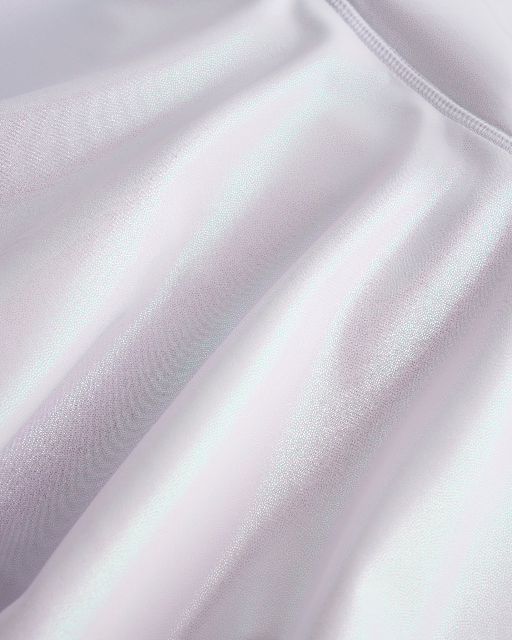 Close-up of white Stelle girls shimmer skort showing iridescent fabric texture and smooth seam detail