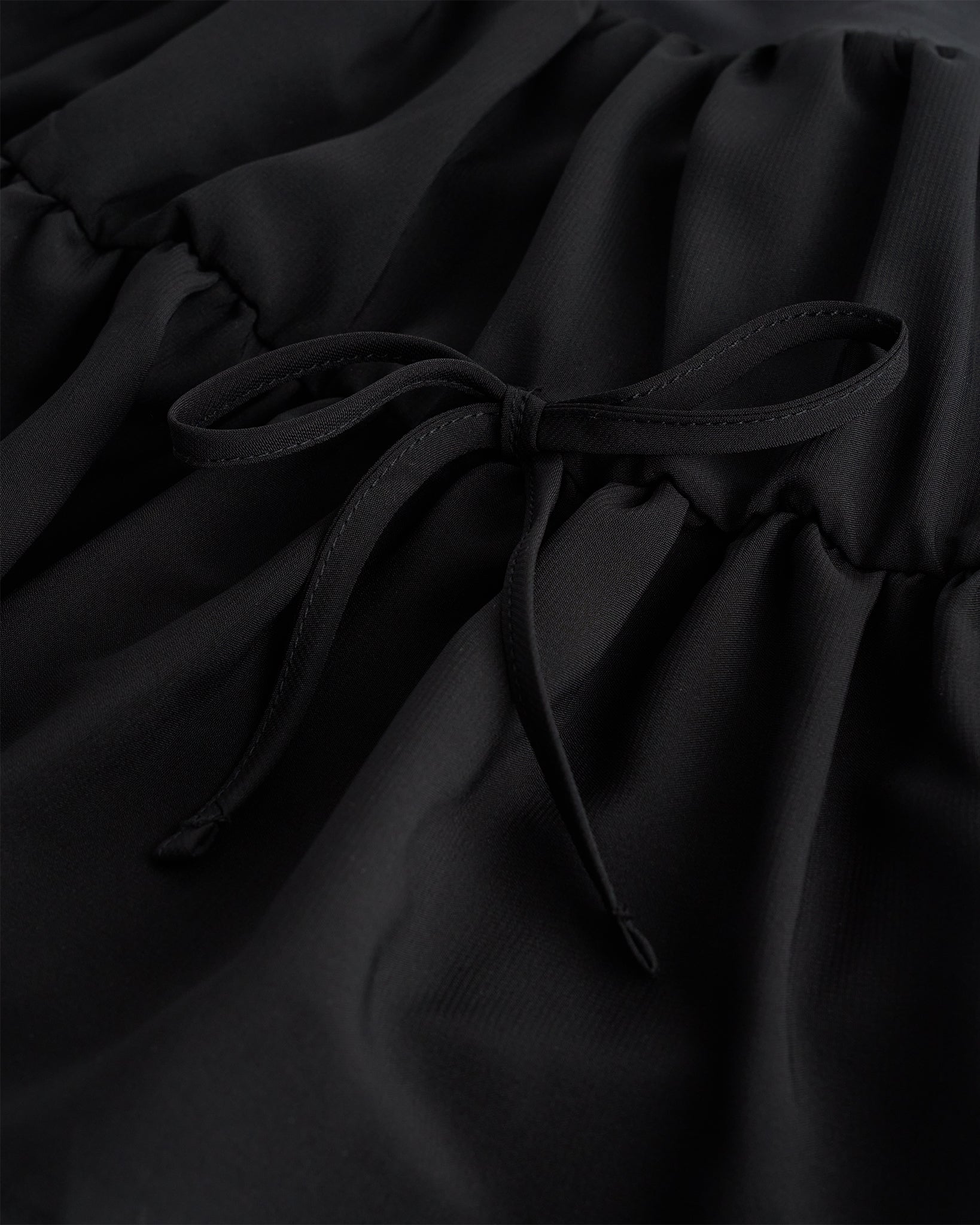 Close-up of black girls tennis skort showing layered chiffon fabric and adjustable tie detail