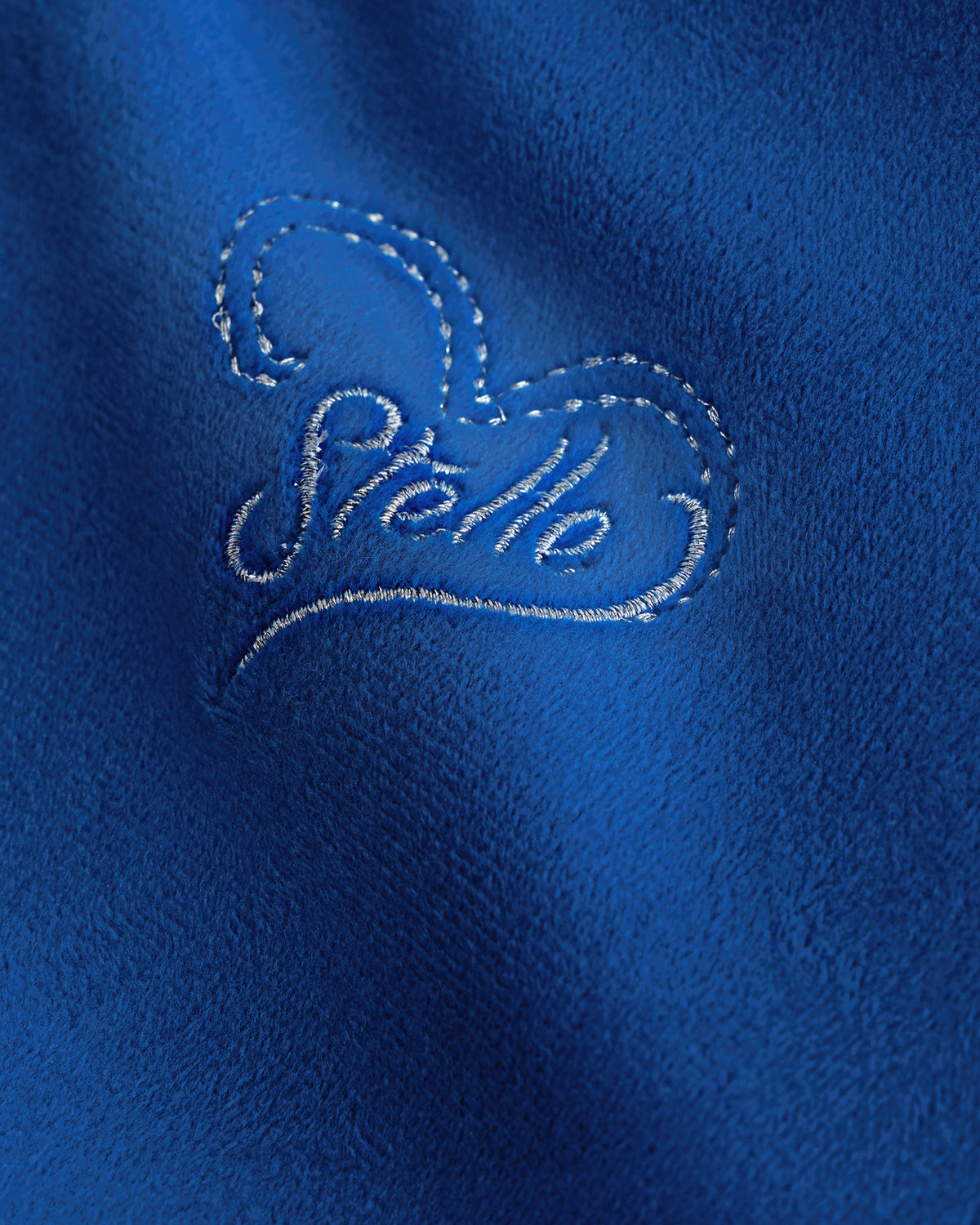 Close-up of the embroidered Stelle heart logo on the Sapphire velour hoodie of the kids tracksuit set.