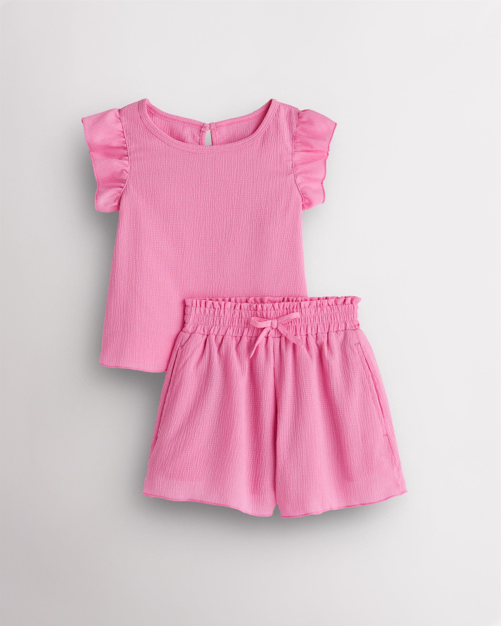 Girls bubblegum flutter sleeve summer outfit set with textured top, button-back detail, and matching elastic waist shorts with bow.