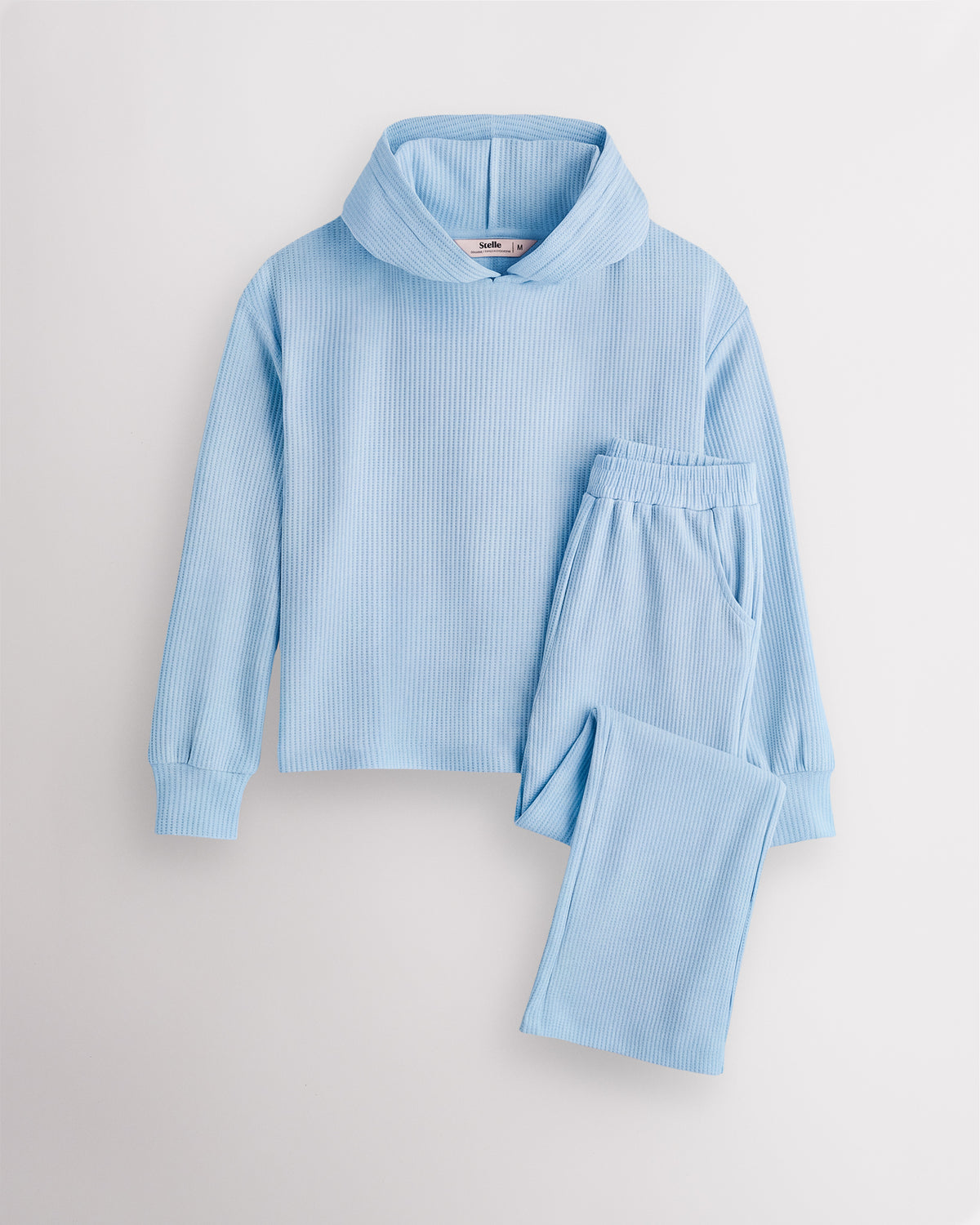 Light Blue Stelle kids waffle knit lounge set with a hooded top and matching pants, laid flat on a grey background.