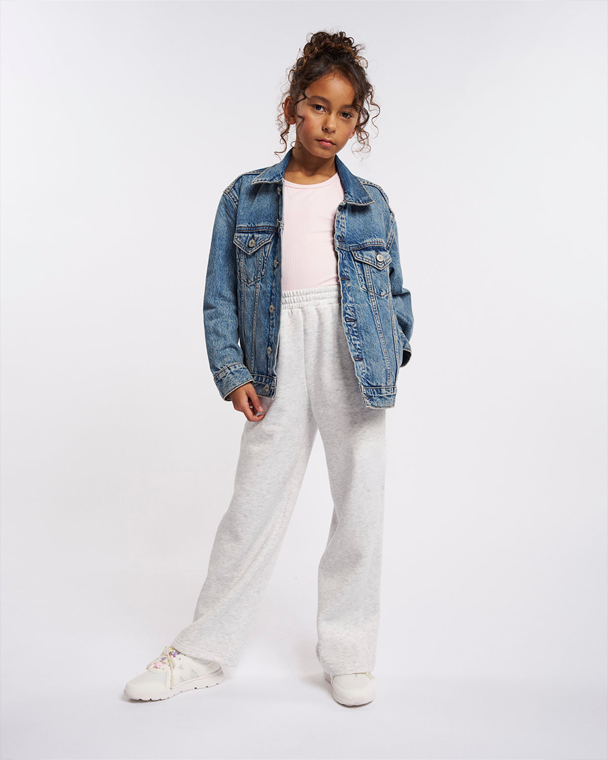 Girl styling Stelle Fleece Out Kids Sweatpants in Light Heather Grey with a denim jacket and white sneakers, casual full-length look