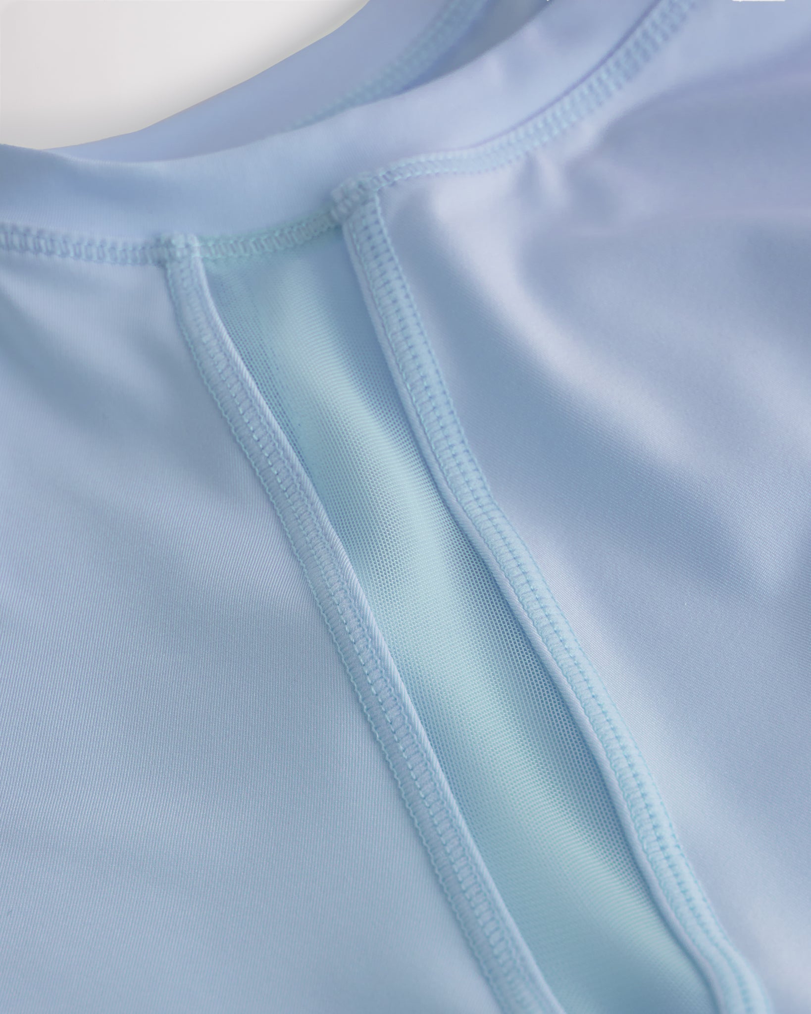Close-up of kids athletic t-shirt mesh panel and flatlock seams showing breathable fabric and stitching detail.