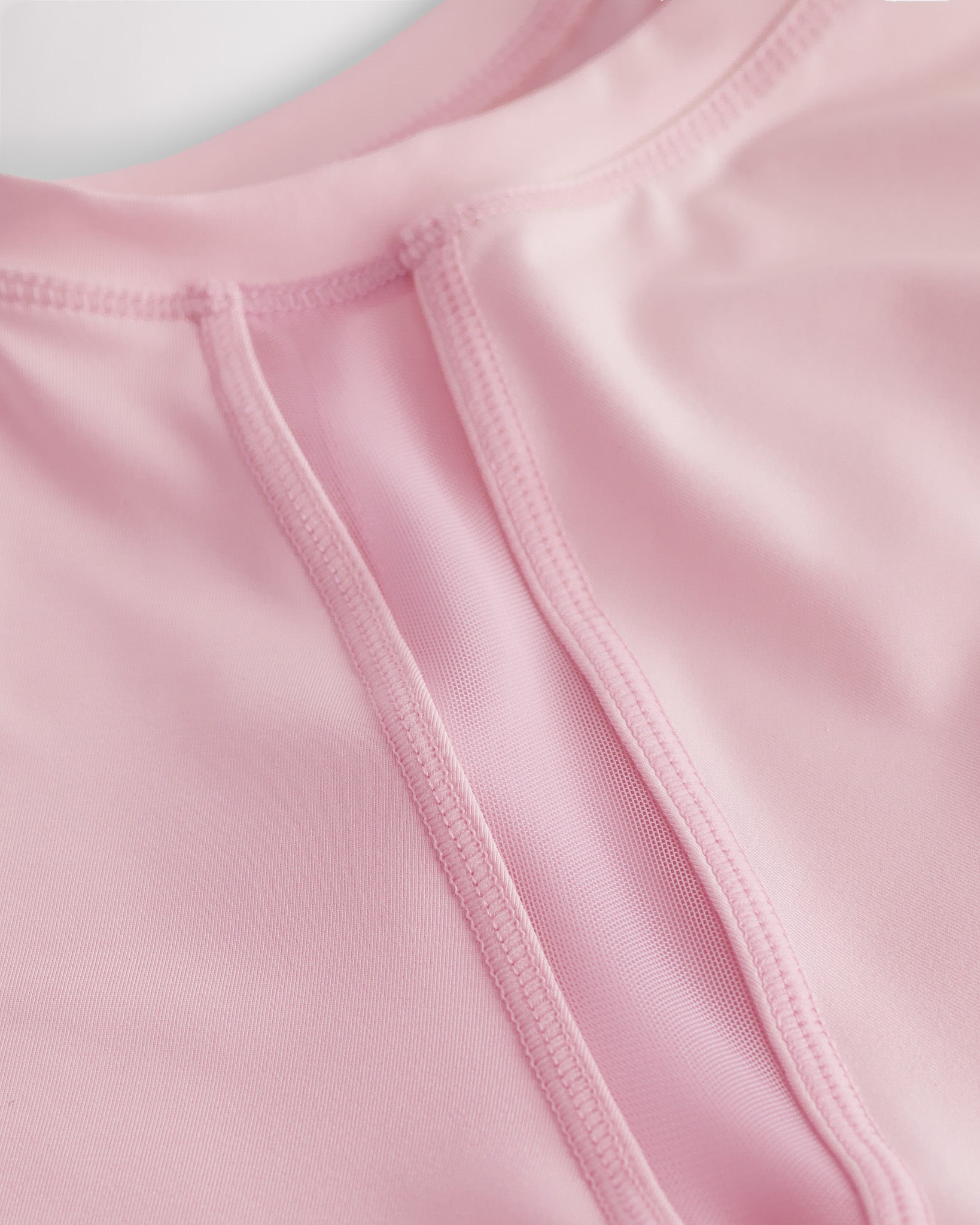 Close-up of kids athletic t-shirt mesh panel and flatlock seams showing breathable fabric and stitching detail.