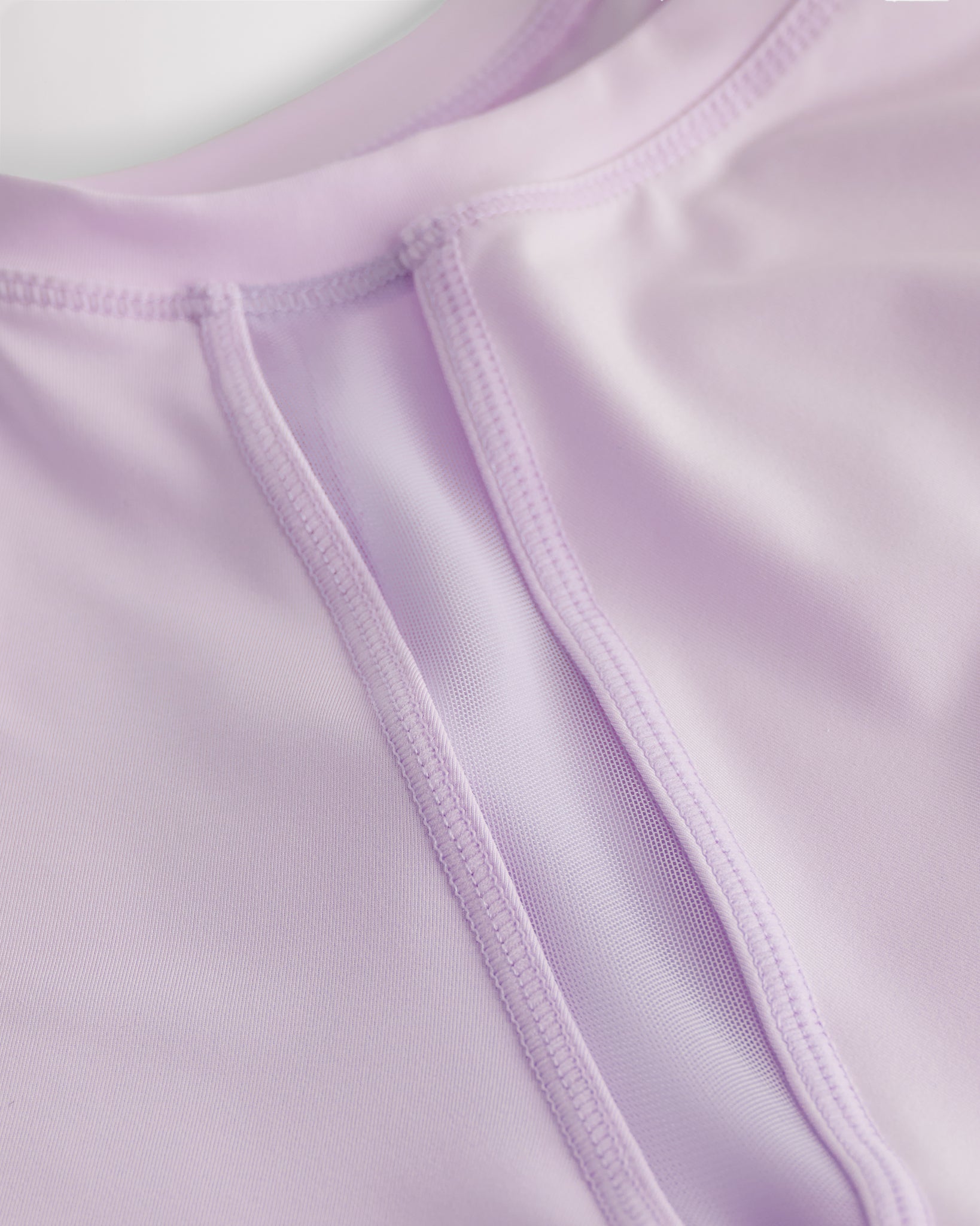 Close-up of kids athletic t-shirt mesh panel and flatlock seams showing breathable fabric and stitching detail.