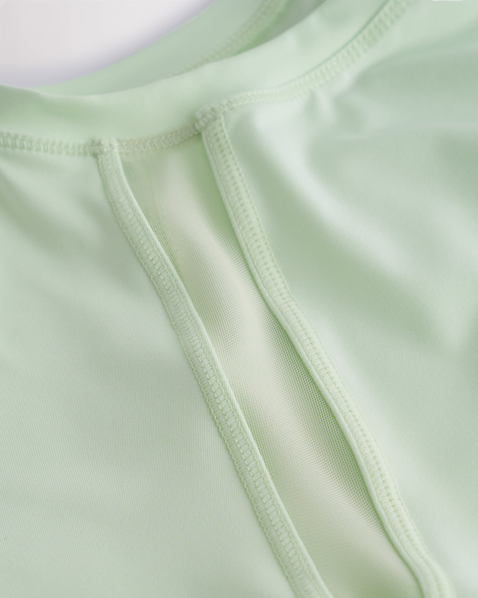 Close-up of kids athletic t-shirt mesh panel and flatlock seams showing breathable fabric and stitching detail.
