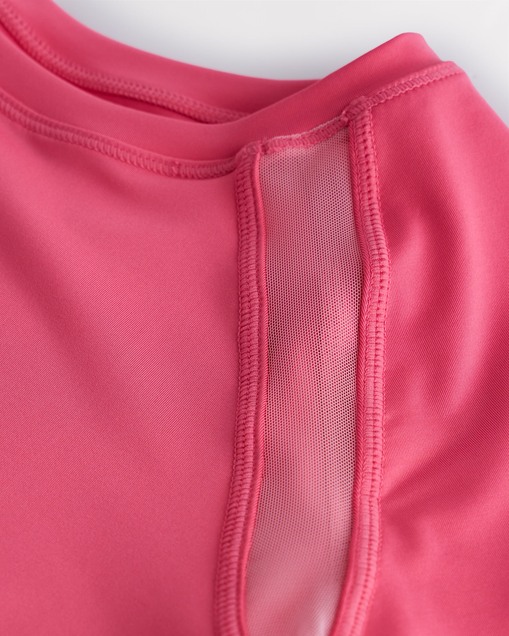 Close-up of kids athletic t-shirt mesh panel and flatlock seams showing breathable fabric and stitching detail.