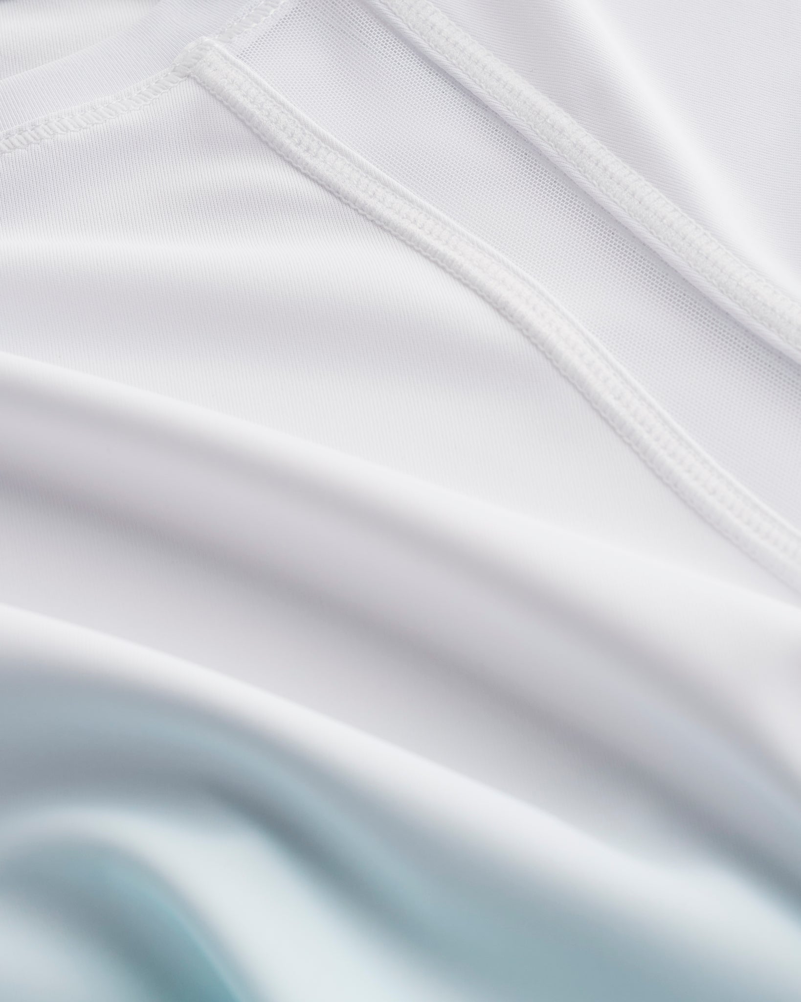 Close-up of Stelle kids ombre athletic t-shirt showing white mesh paneling, smooth seams, and aque blue gradient fabric
