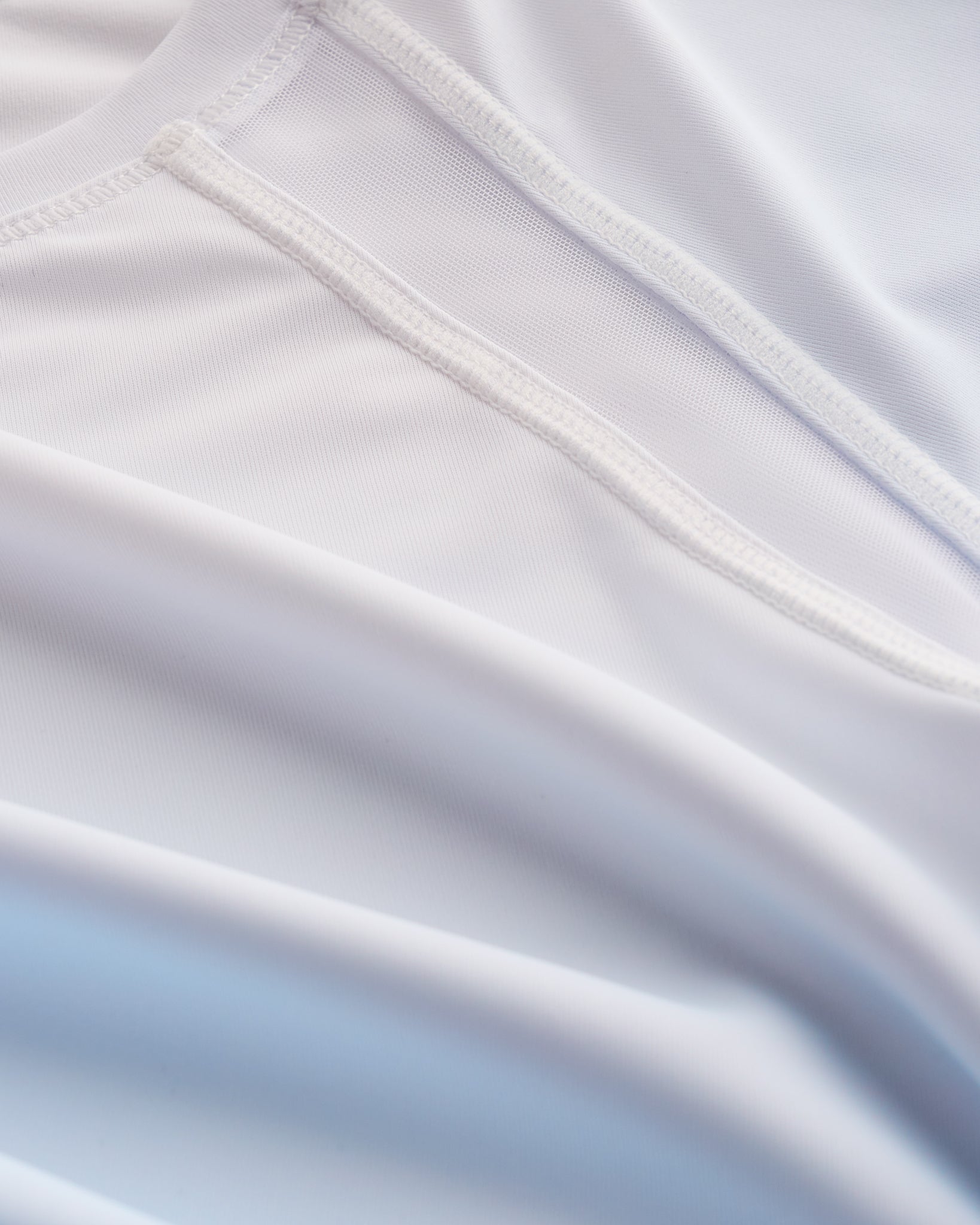Close-up of Stelle kids ombre athletic t-shirt showing white mesh paneling, smooth seams, and light blue gradient fabric.
