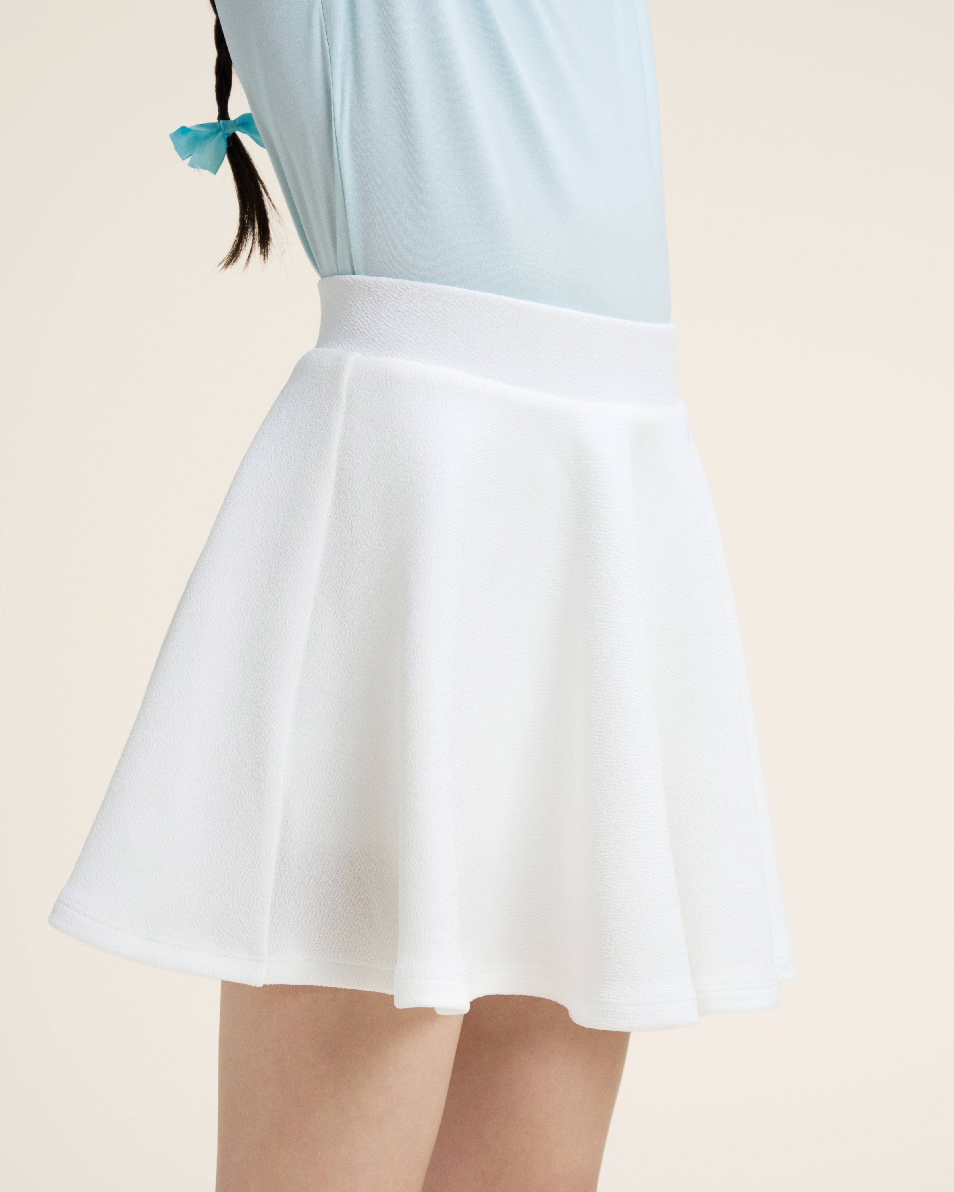 White skirt worn by a person on a beige background